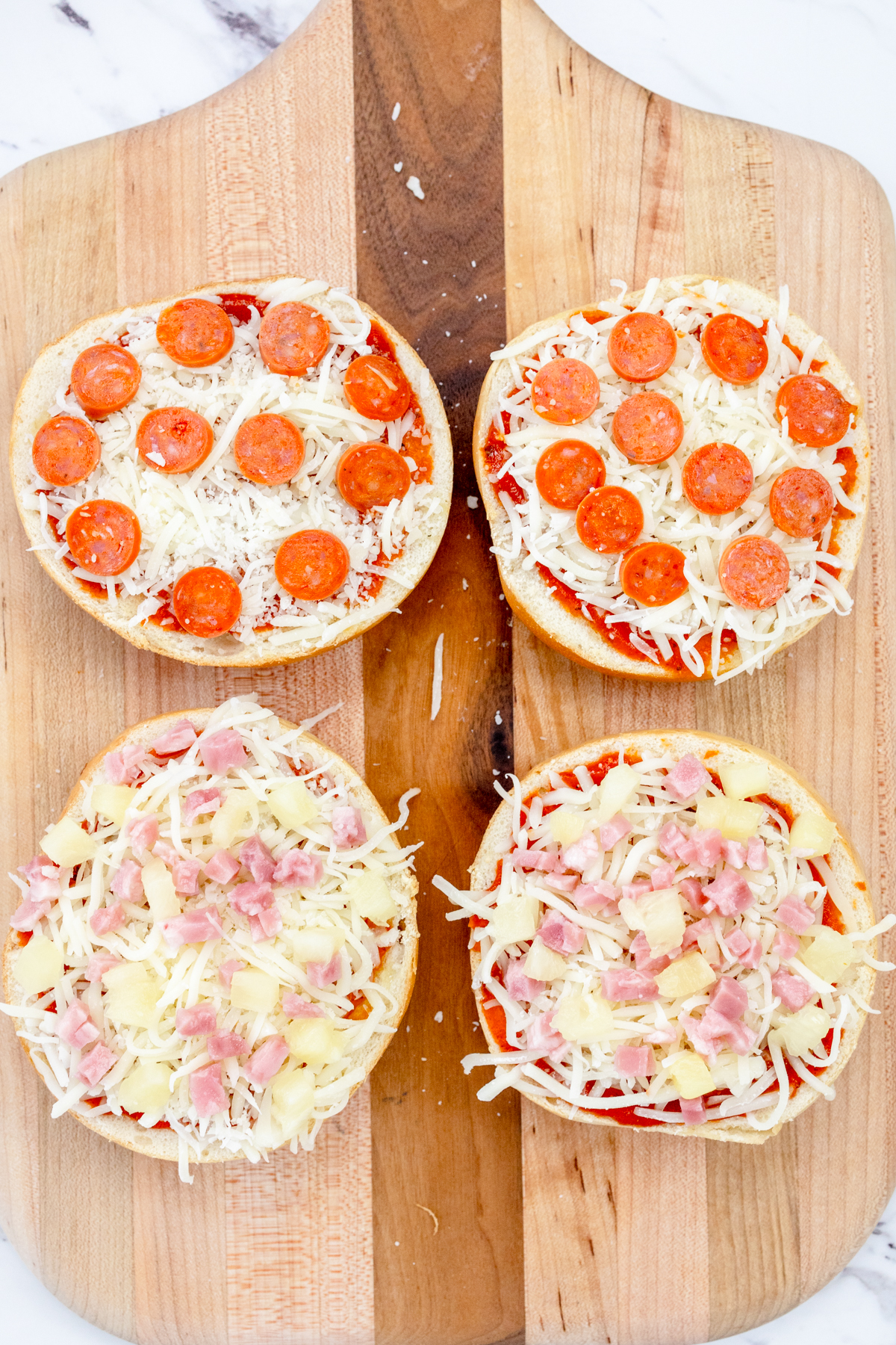 Top view of Air Fryer Pizza Bagels on a wooden chopping board, ready to be fried.