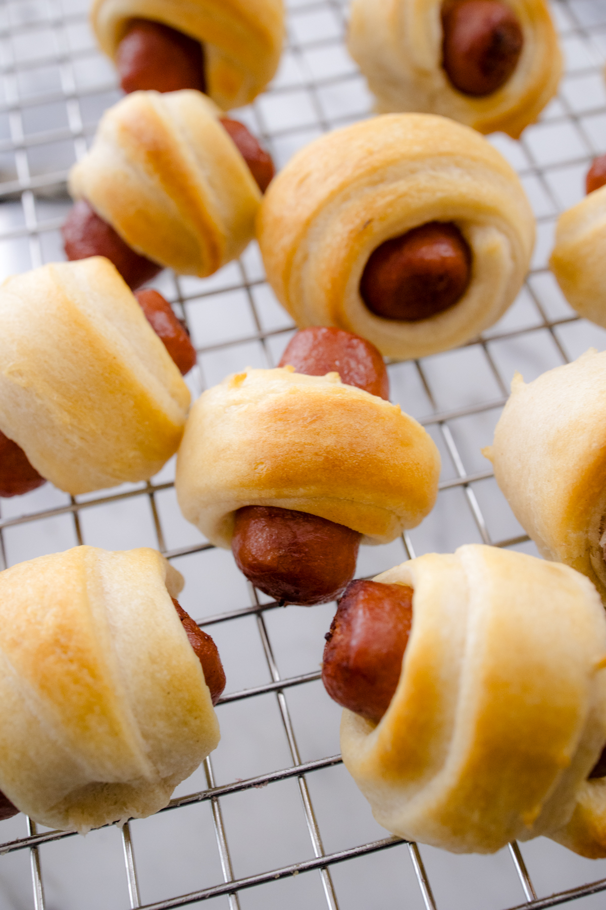 Close up view of cooked Pigs in a Blanket on a wire rack.