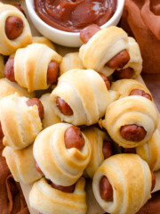 Close up view of air fried Pigs in a Blanket on a countertop with decorations next to a ramekin filled with tomato ketchup.