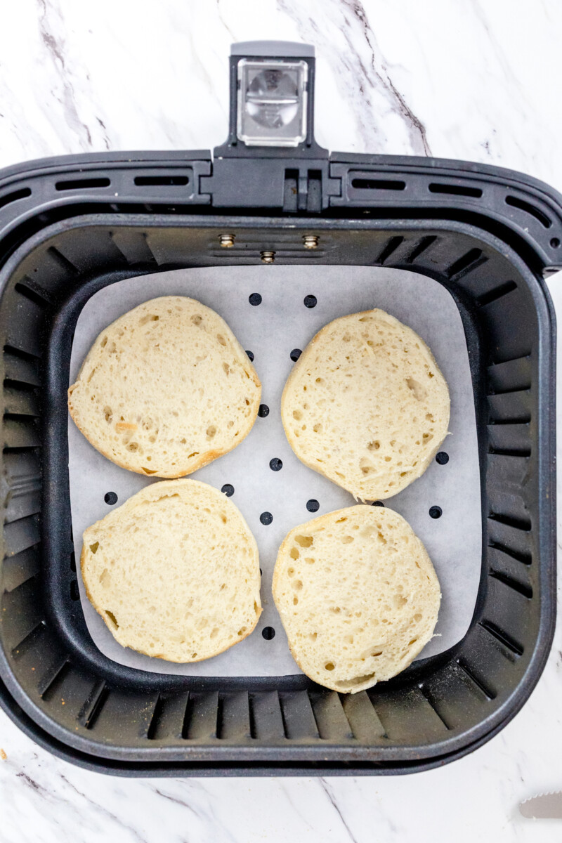 Top view of English muffin slices in an air fryer.