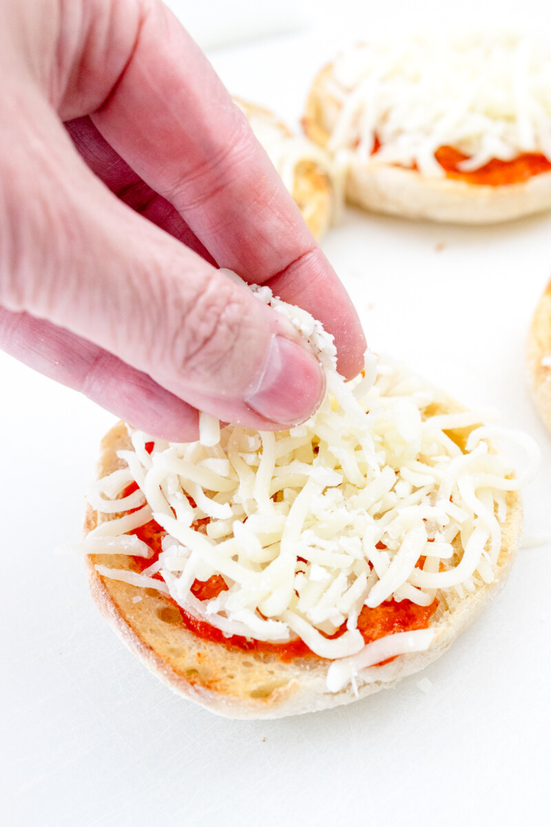 Close up view of mozzarella cheese being added to a muffin.