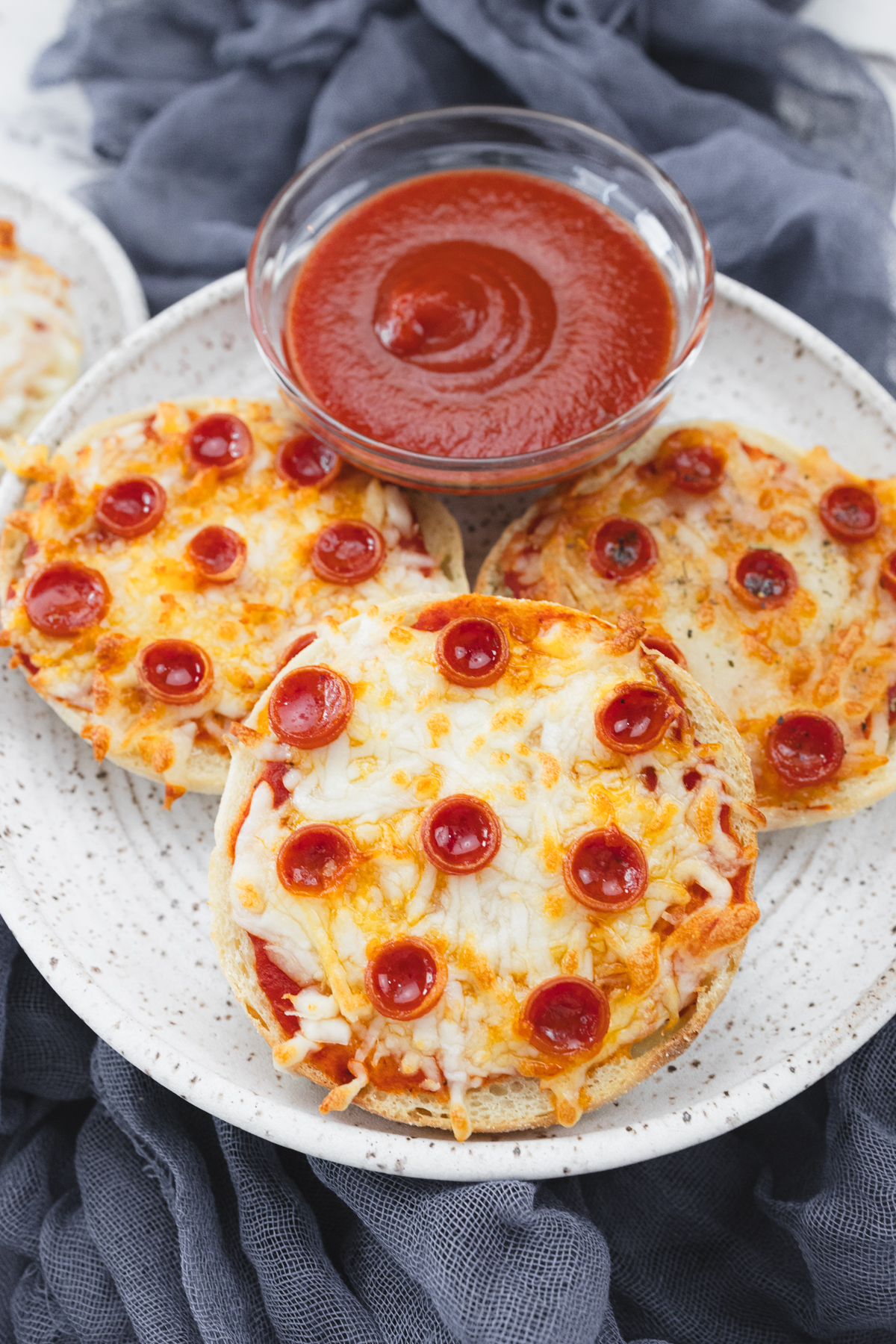 Close up view of cooked English Muffin Pizzas on a white plate.