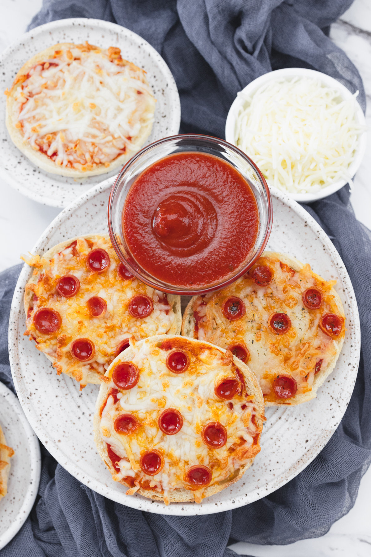 Top view of Close up view of cooked English Muffin Pizzas on a white plate.