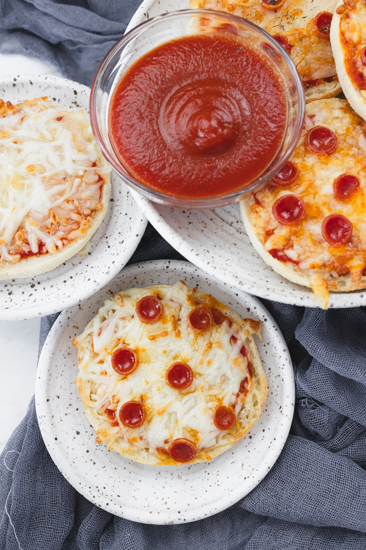 Top view of Close up view of cooked English Muffin Pizzas on a white plate.