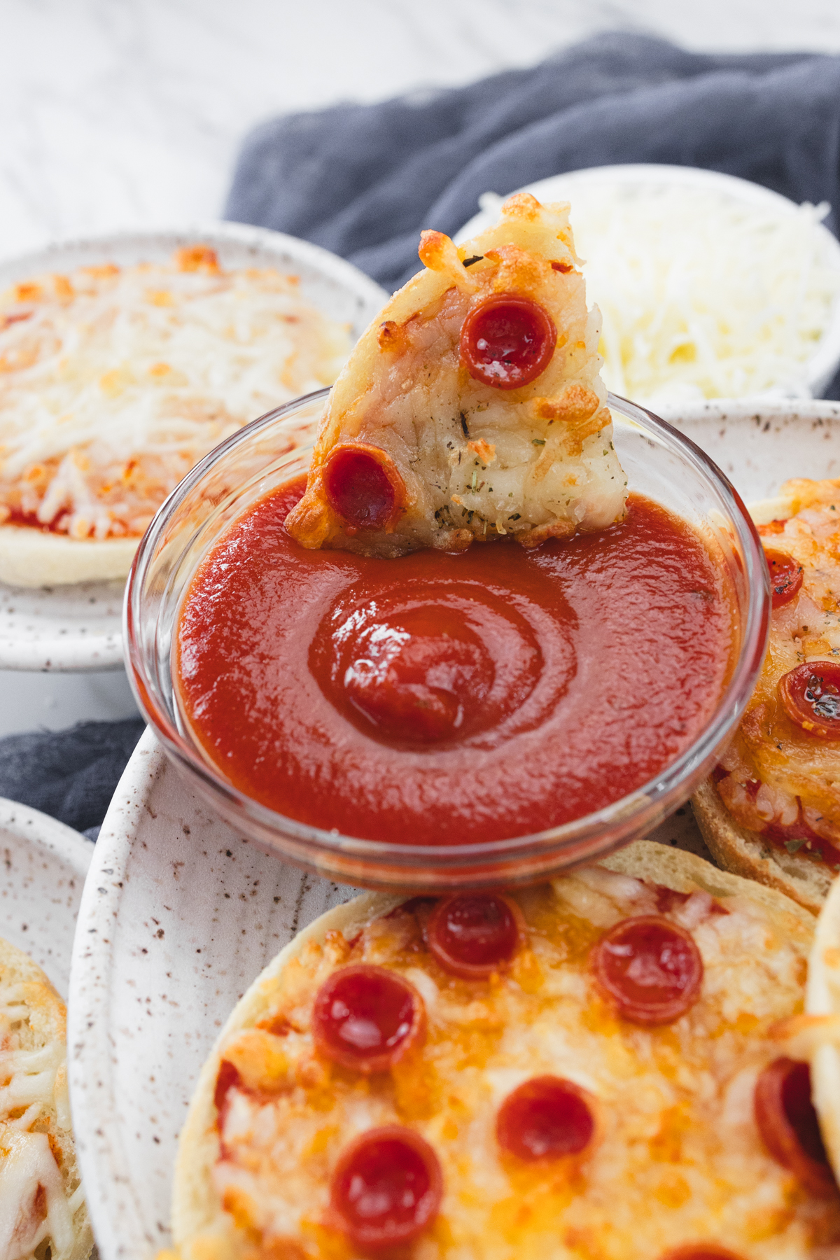 Close up view of sliced English Muffin Pizzas being dipped in sauce.