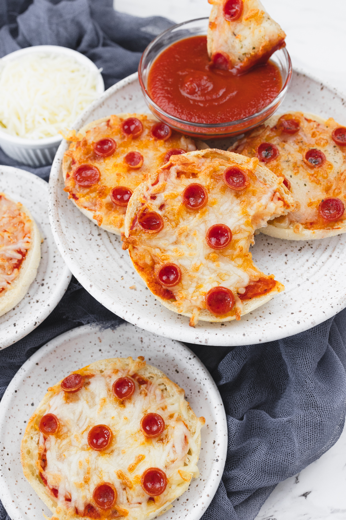 Top view of cooked English Muffin Pizzas on a white plate.