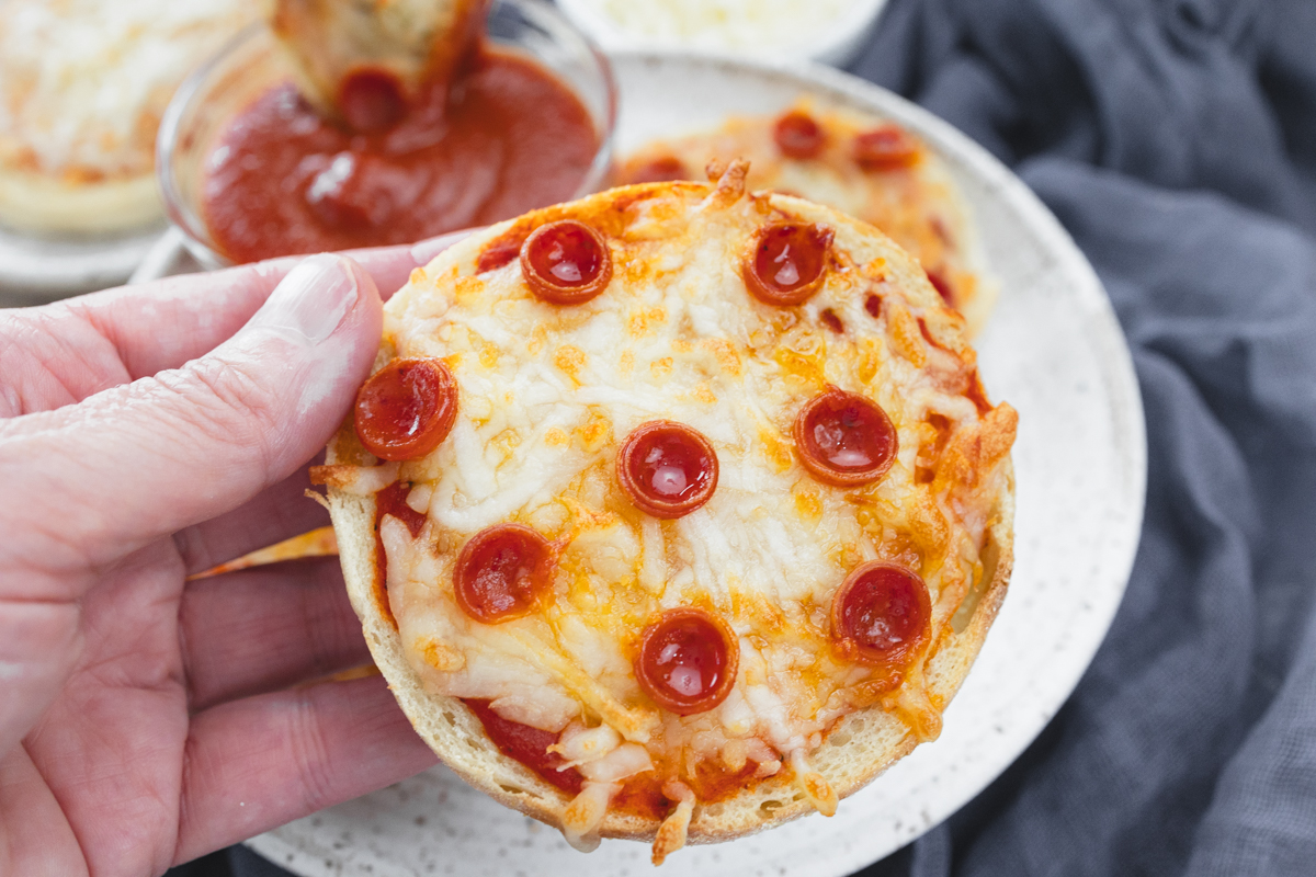 Close up view of cooked English Muffin Pizzas on a white plate.