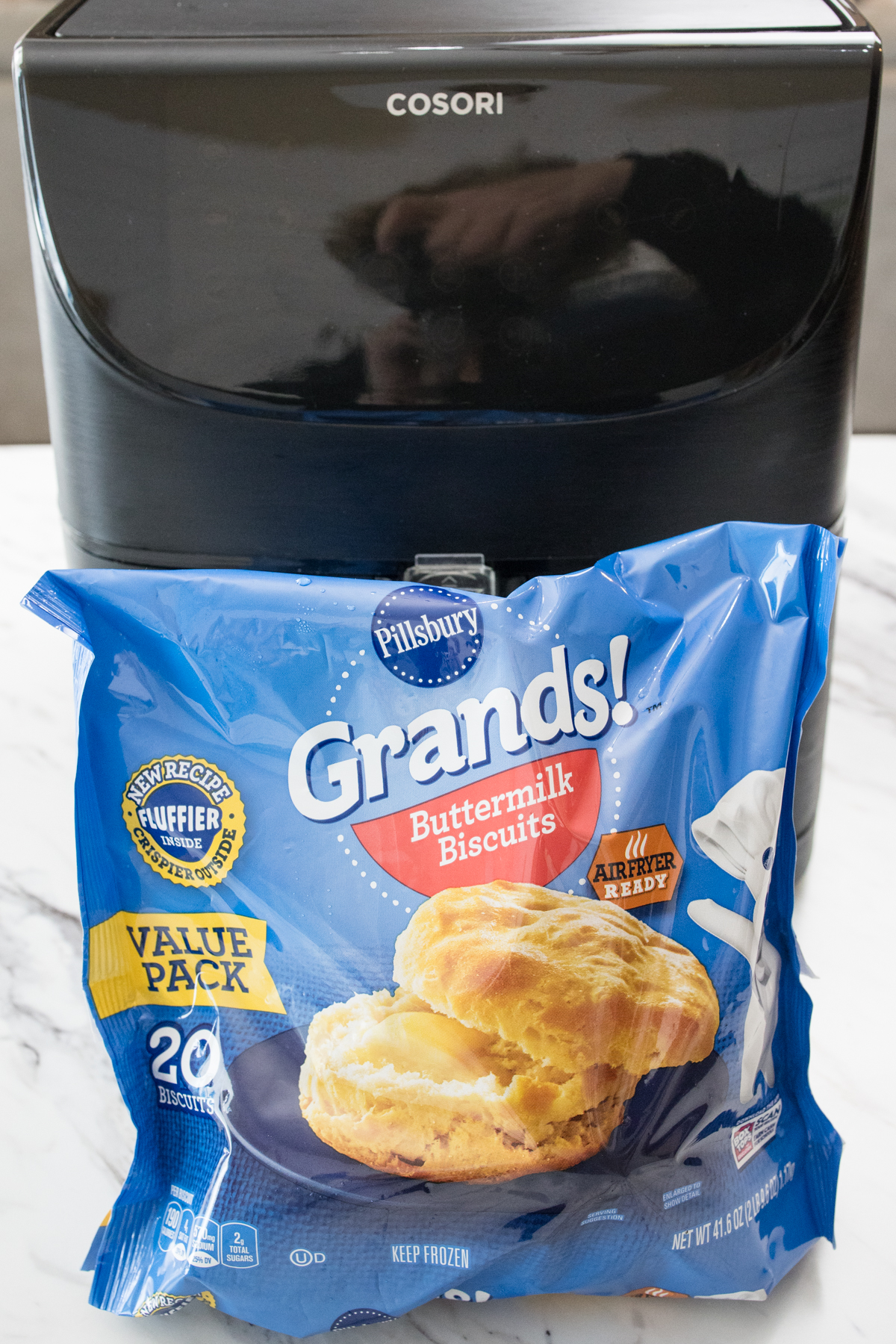 Close up view of a bag of Pillsbury Grands biscuits in front of an air fryer.