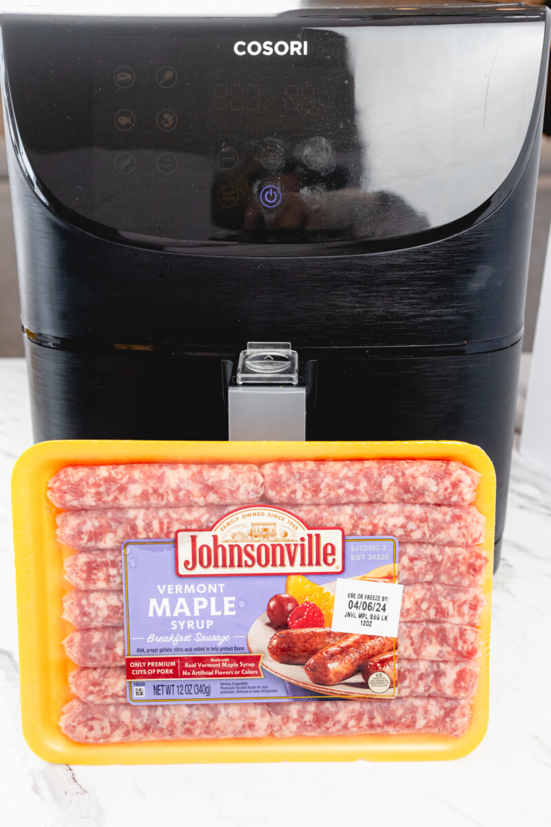 A pack of sausage links in front of an air fryer.