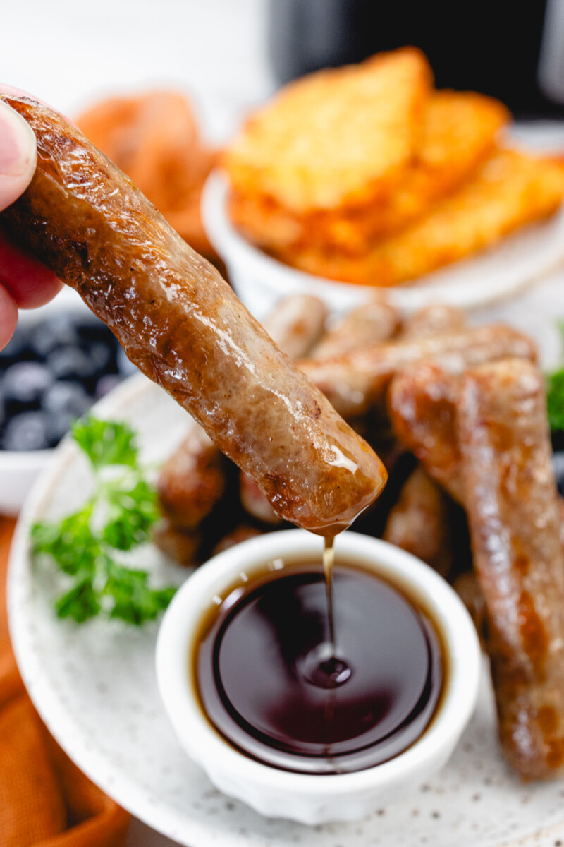 A close up view of a sausage being dipped in gravy.