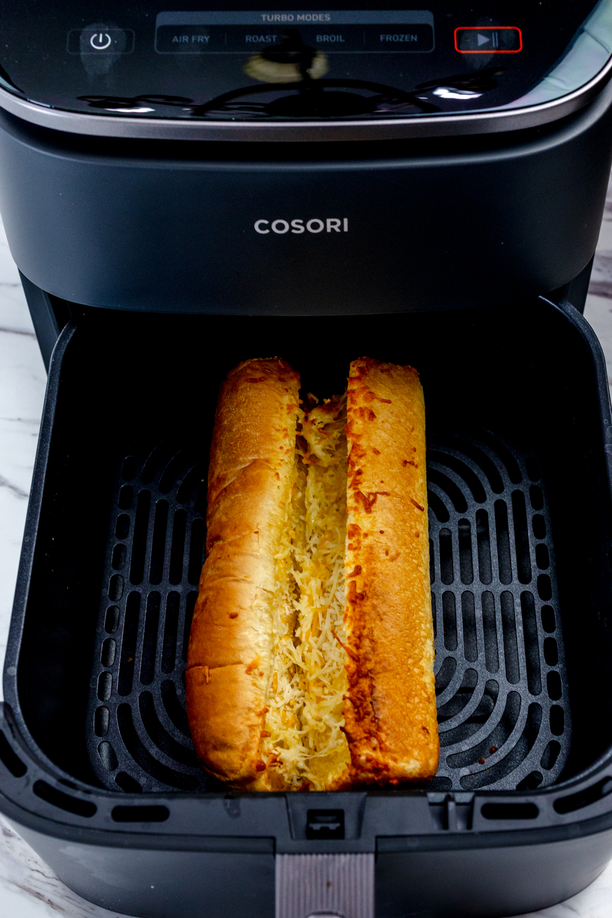 Top view of a cooked garlic bread loaf in an air fryer basket.