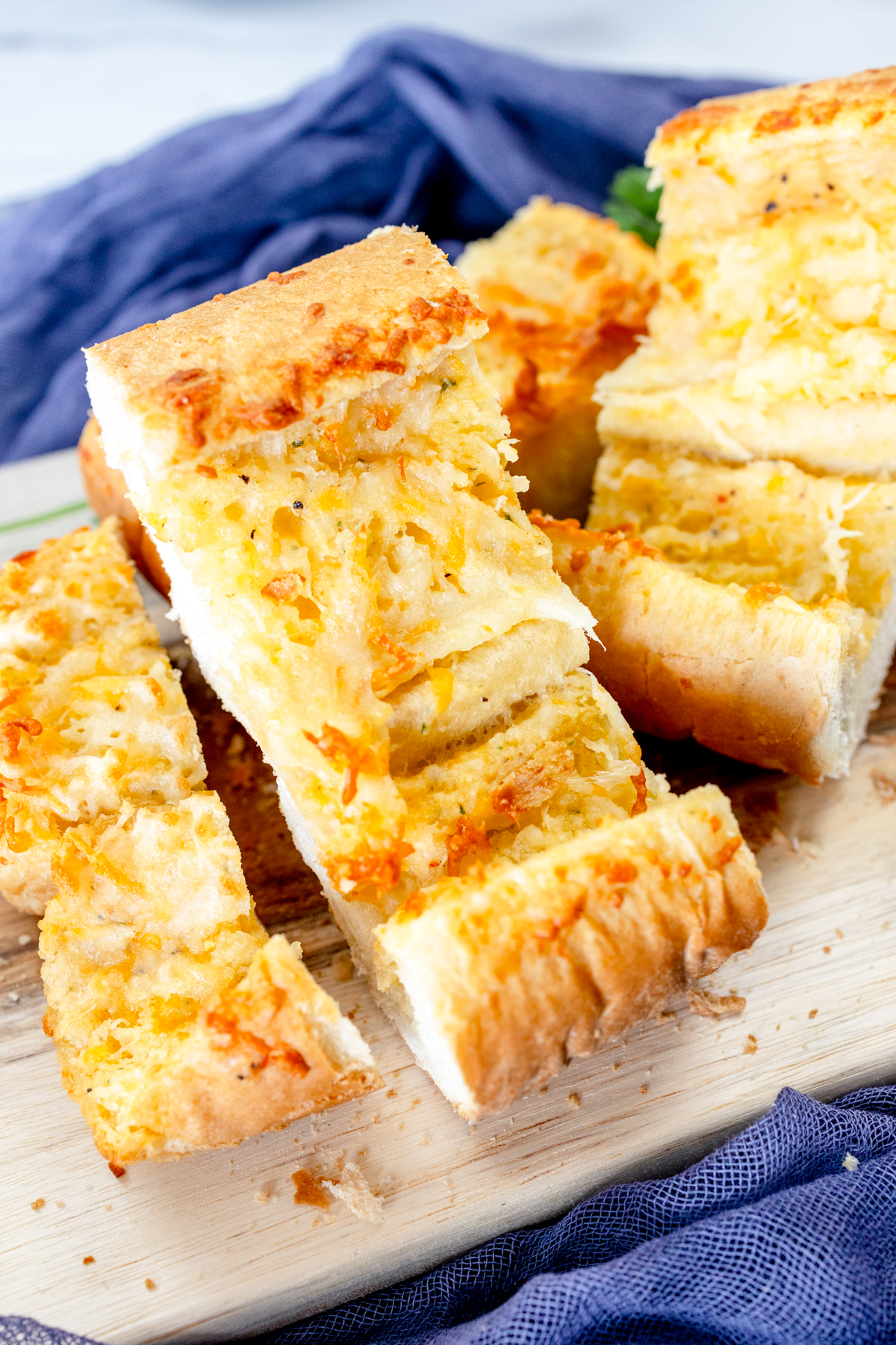 Close up image of air fried garlic bread on a wooden chopping board.