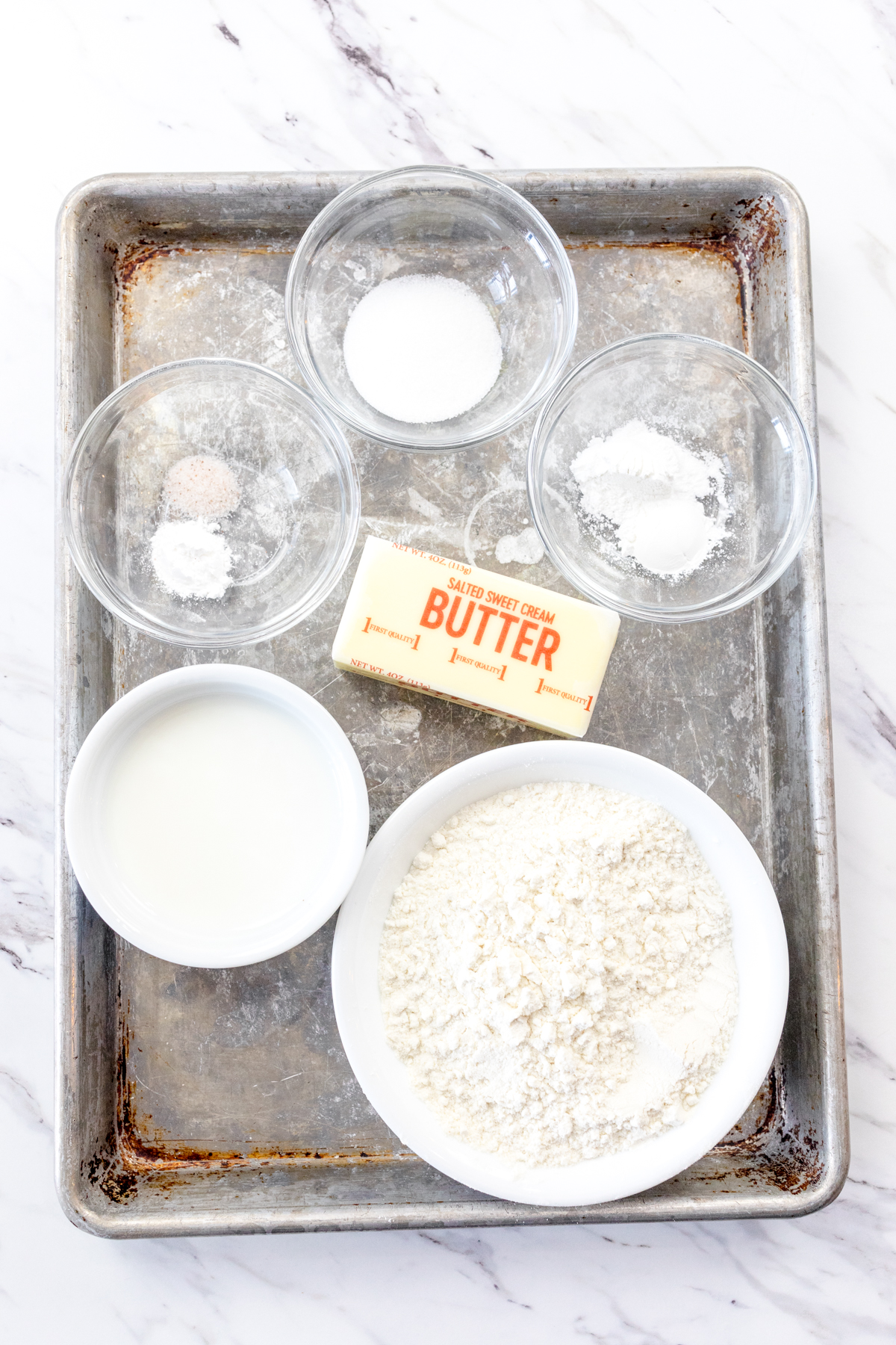 Top view of ingredients needed to make Air Fryer Biscuits in small bowls on a baking tray.