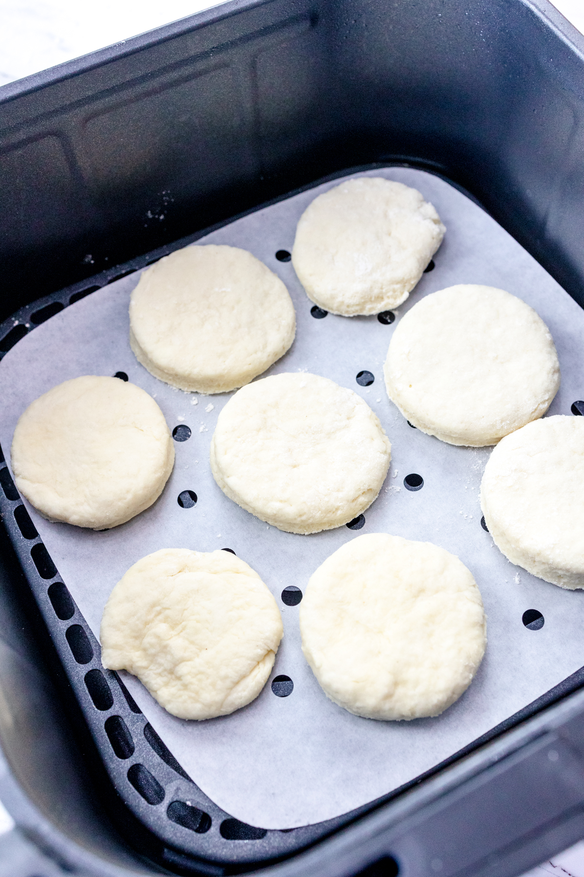 Close up view of uncooked Air Fryer Biscuits in an air fryer basket.