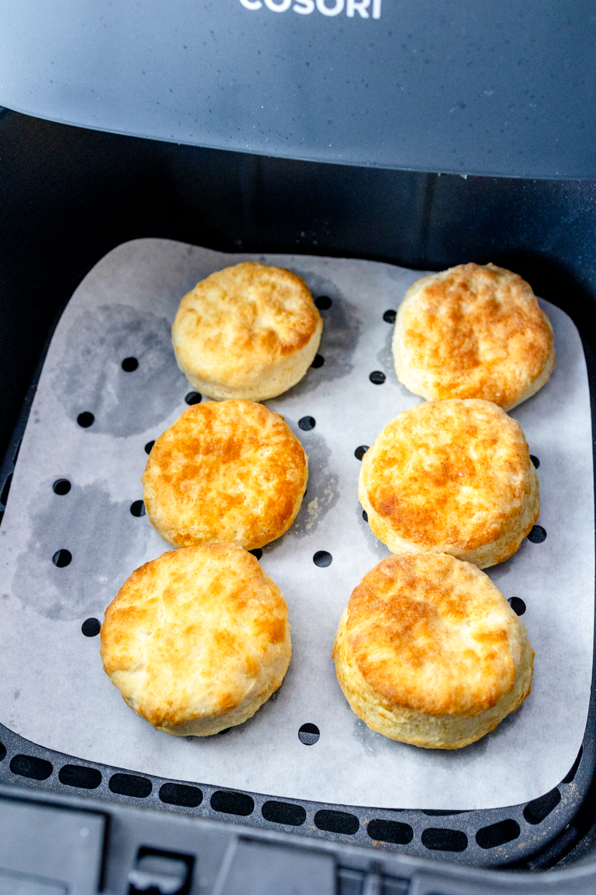 Cooked biscuits in an air fryer basket.