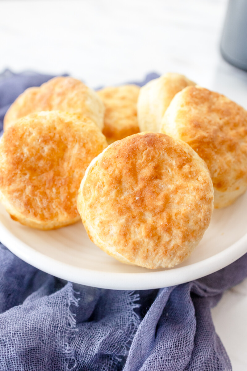 Close up view of cooked Air Fryer Biscuits on a white plate.