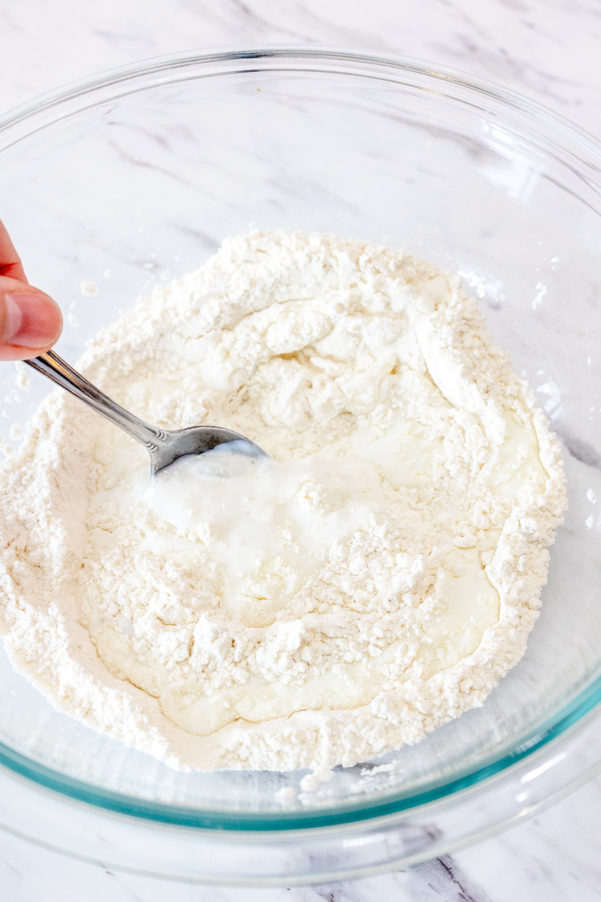 Close up image of buttermilk being combined with the dry ingredients for butter swim biscuits.