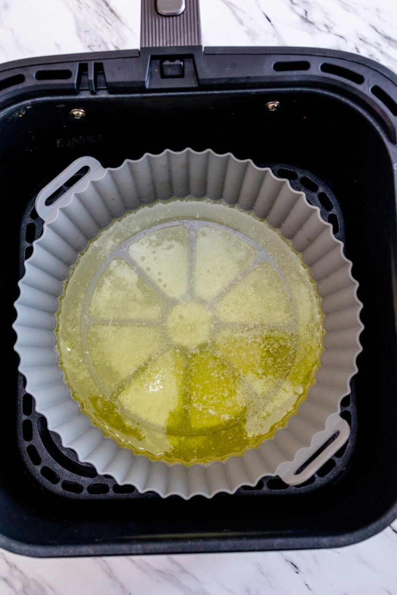 A top view of a silicone baking dish with melted butter in it, in an air fryer.