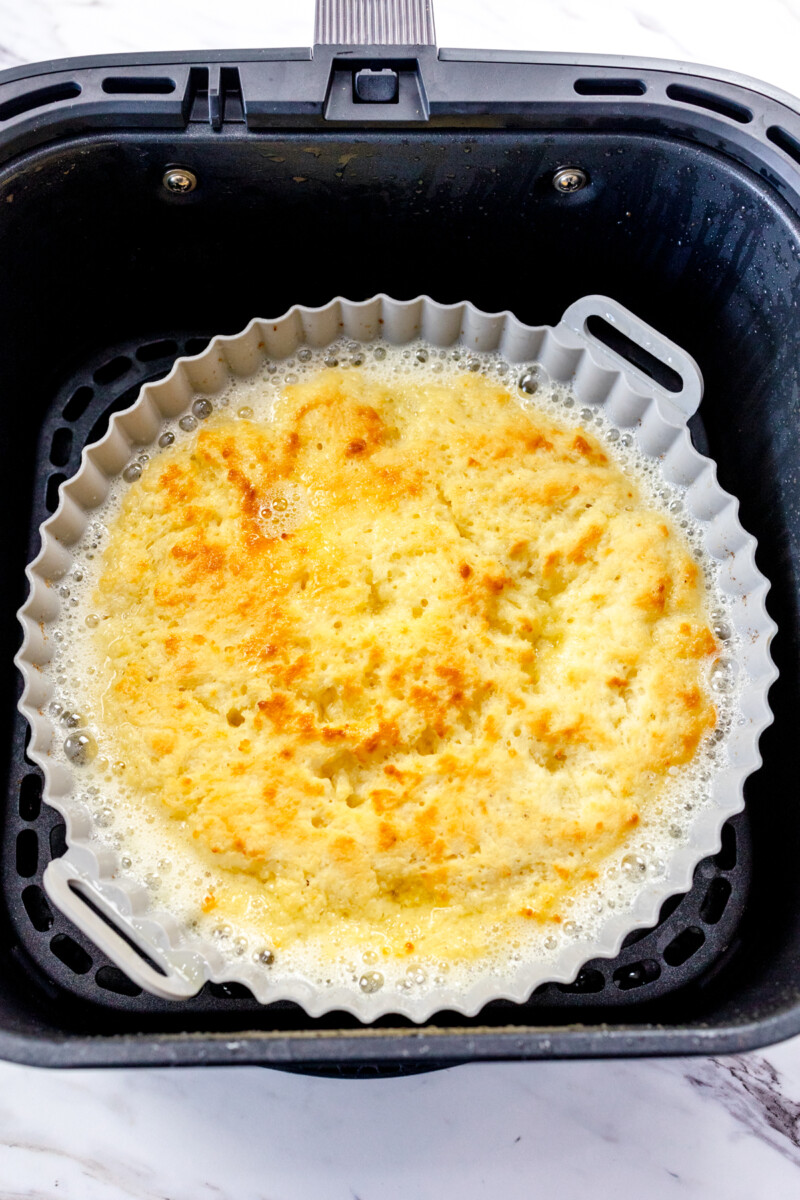 A top view of a silicone baking dish in an air fryer with cooked butter swim biscuits in it.