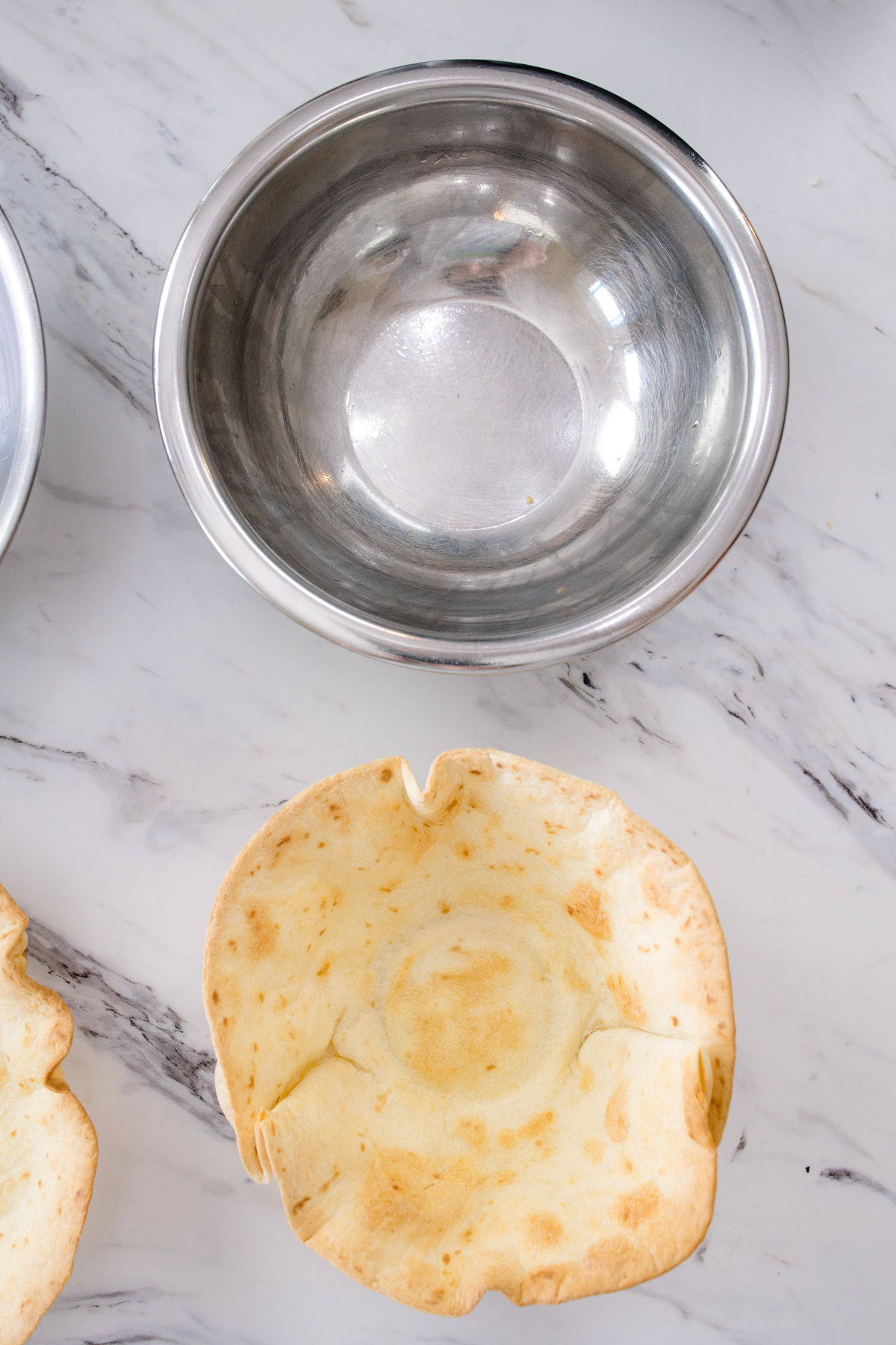 Top view of a metal bowl next to an Air Fryer Flour Tortilla Bowl.