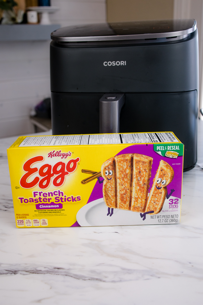 A box of Kellog's Eggo French Toaster Sticks in front of an air fryer.