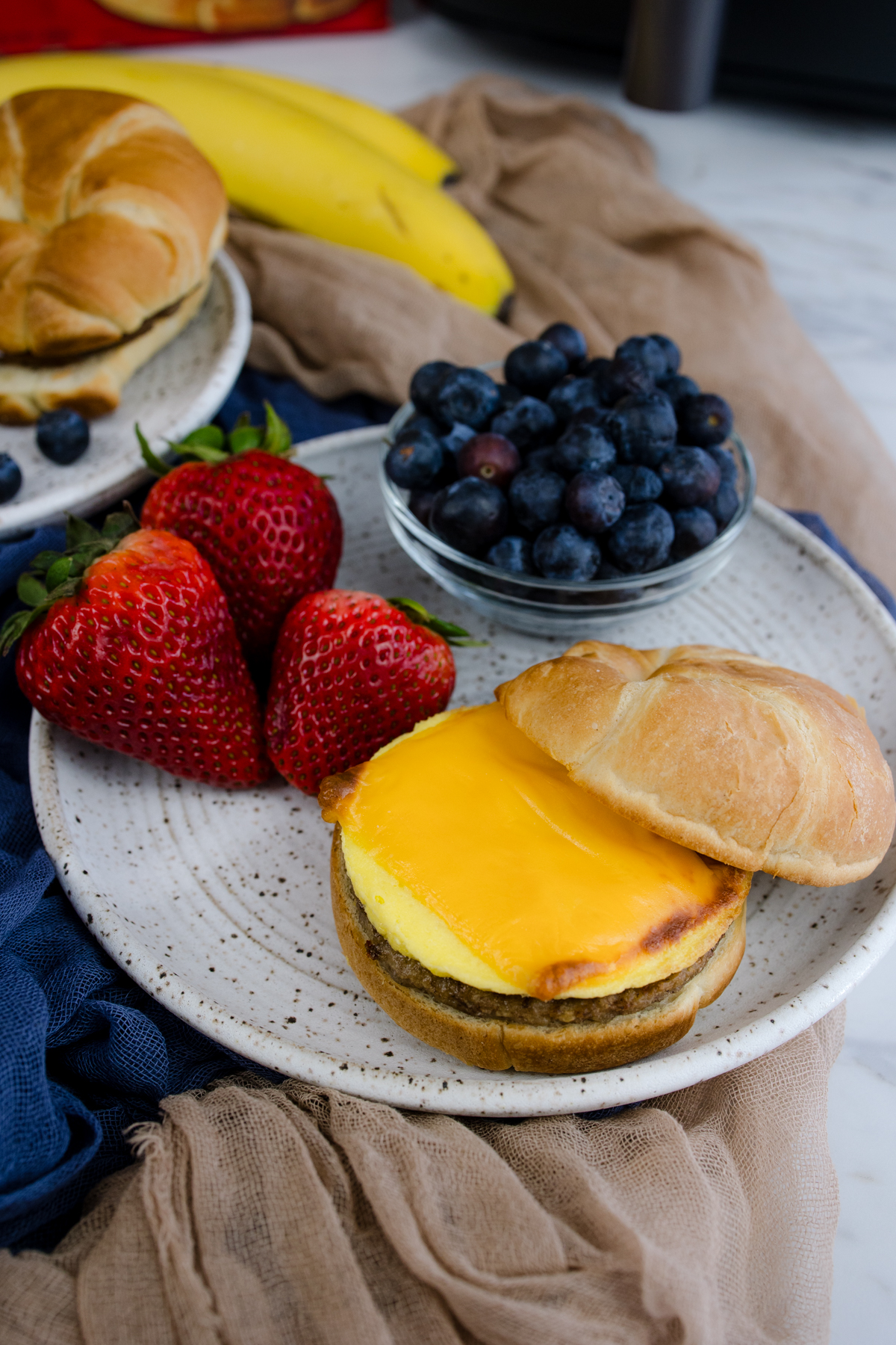 Jimmy Dean Breakfast Sandwich on a plate with strawberries and blueberries.