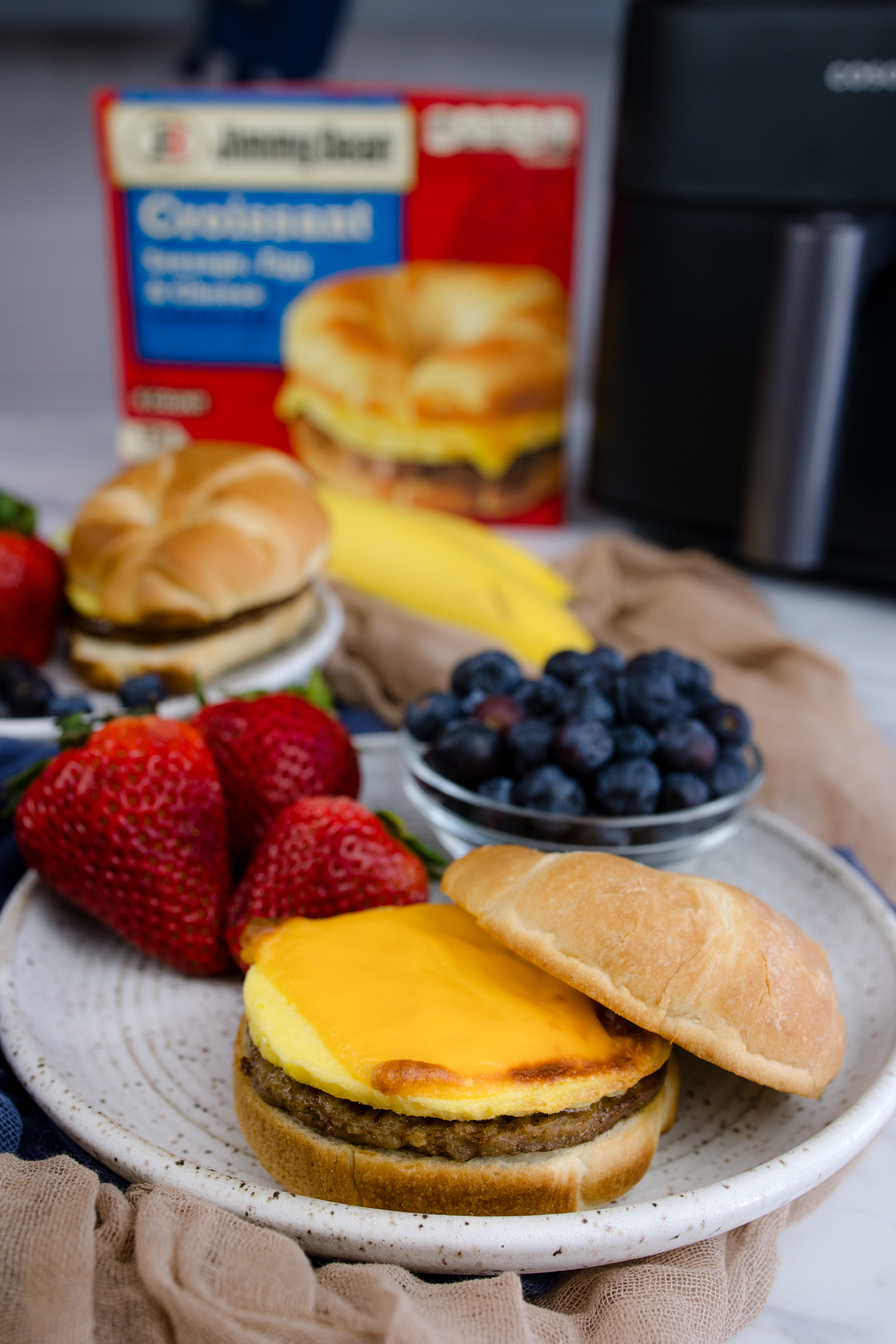 Jimmy Dean Breakfast Sandwich on a plate with strawberries and blueberries.