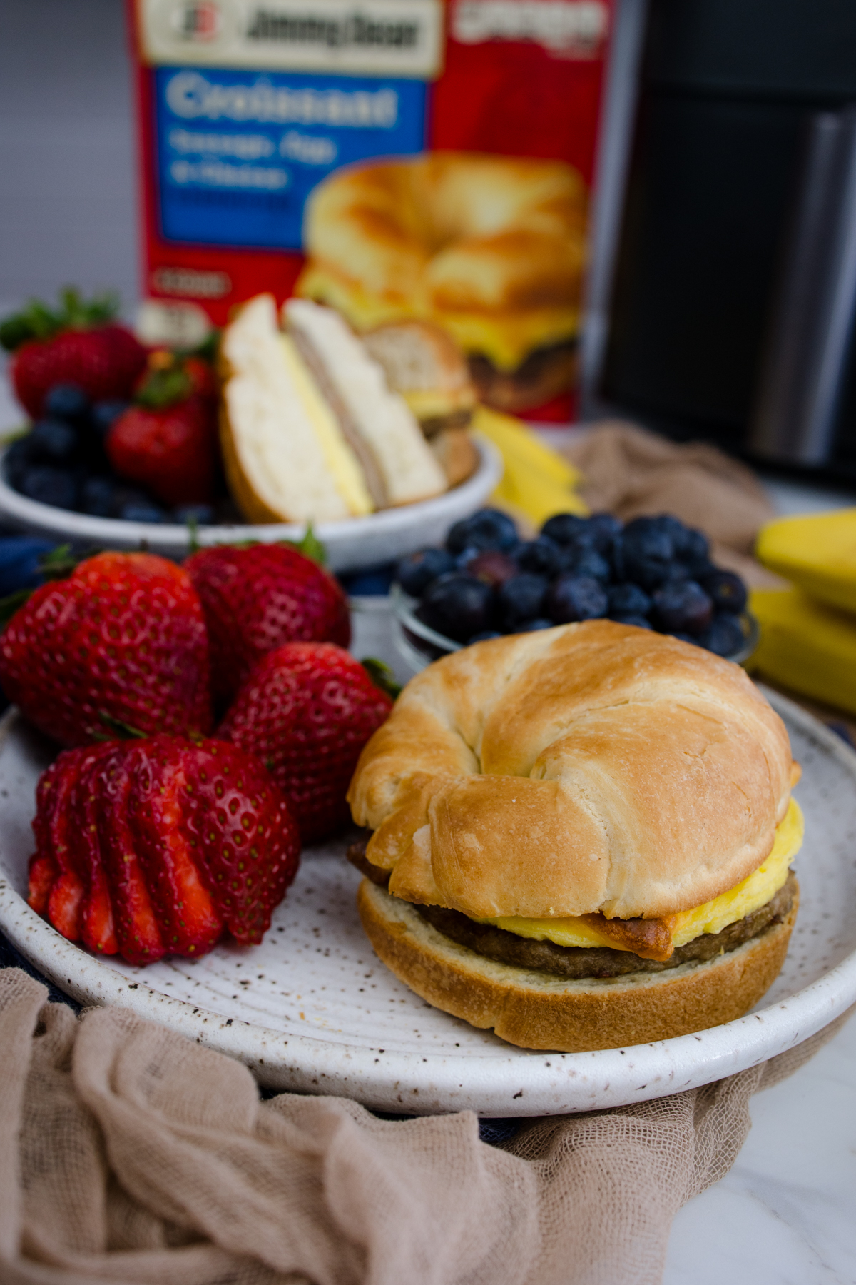 Jimmy Dean Breakfast Sandwich on a plate with strawberries and blueberries.