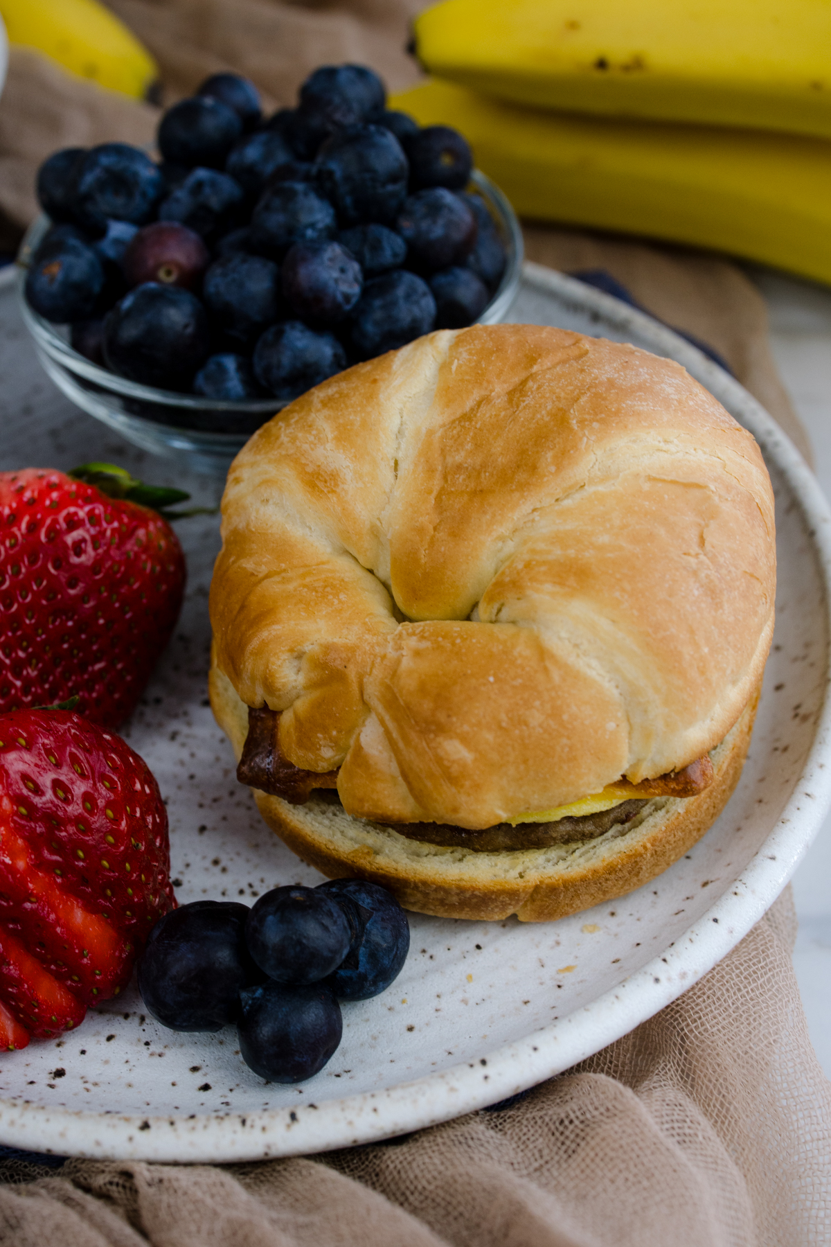 Jimmy Dean Breakfast Sandwich on a plate with strawberries and blueberries.