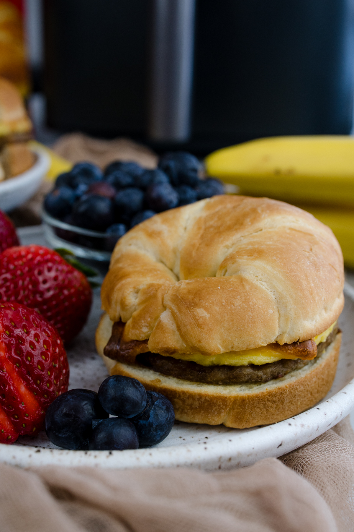 Jimmy Dean Breakfast Sandwich on a plate with strawberries and blueberries.