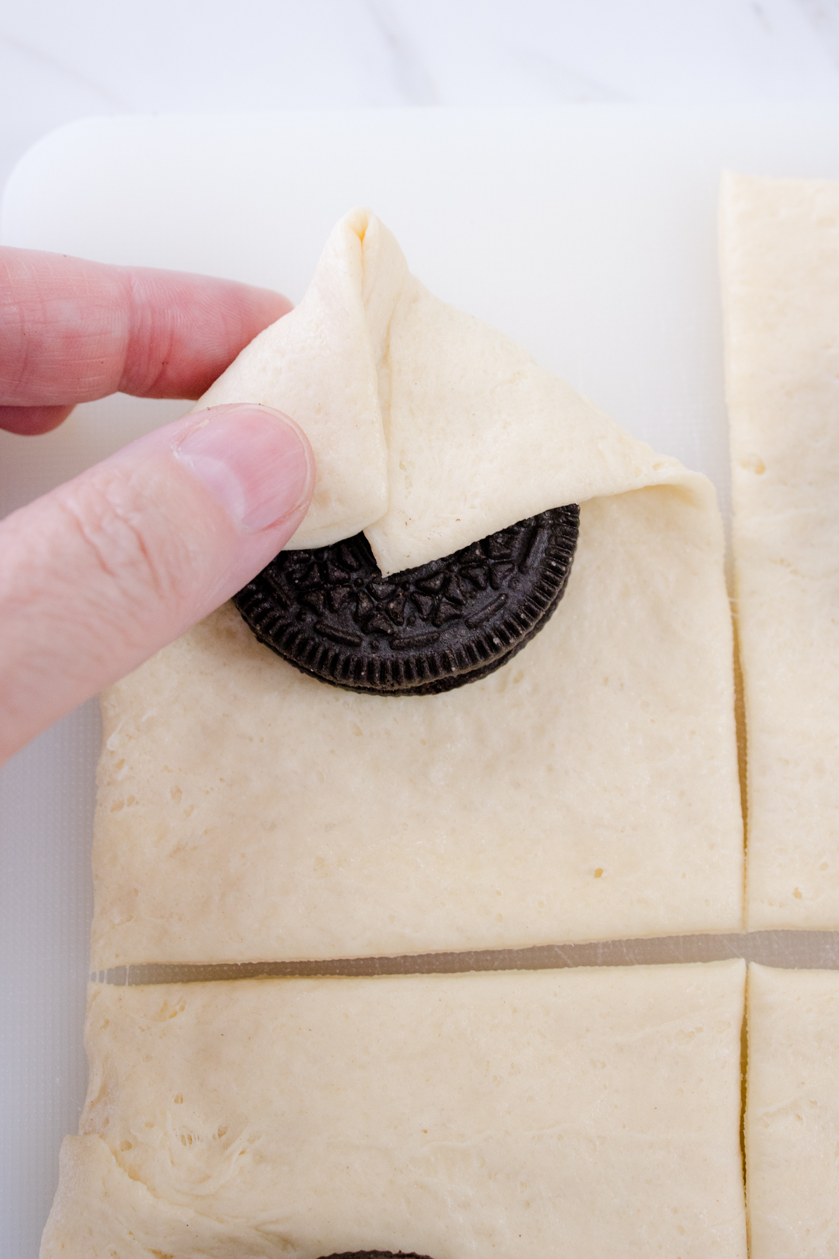 Oreos being wrapped in squares of dough.