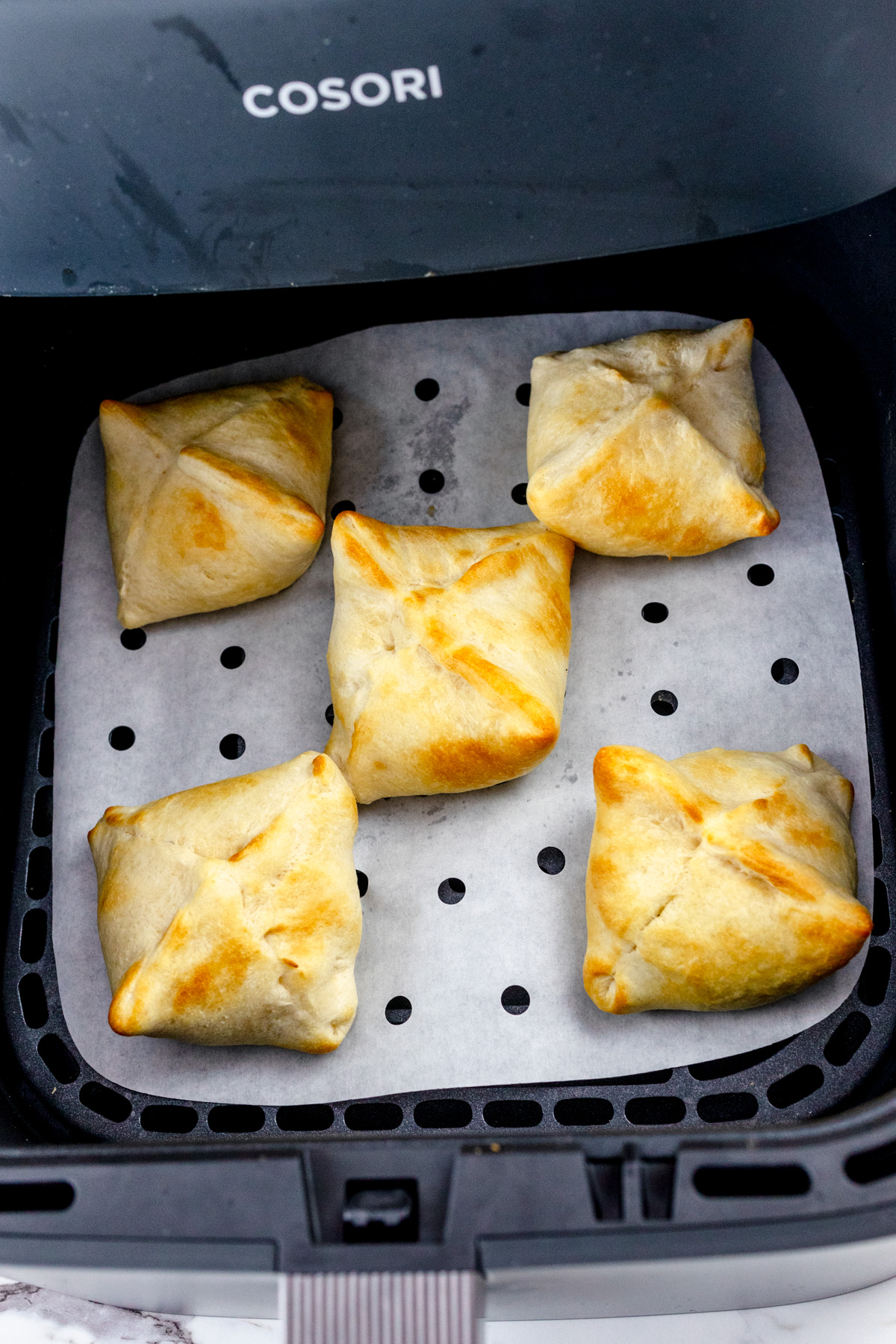 Cooked cough-wrapped oreos in an air fryer basket.