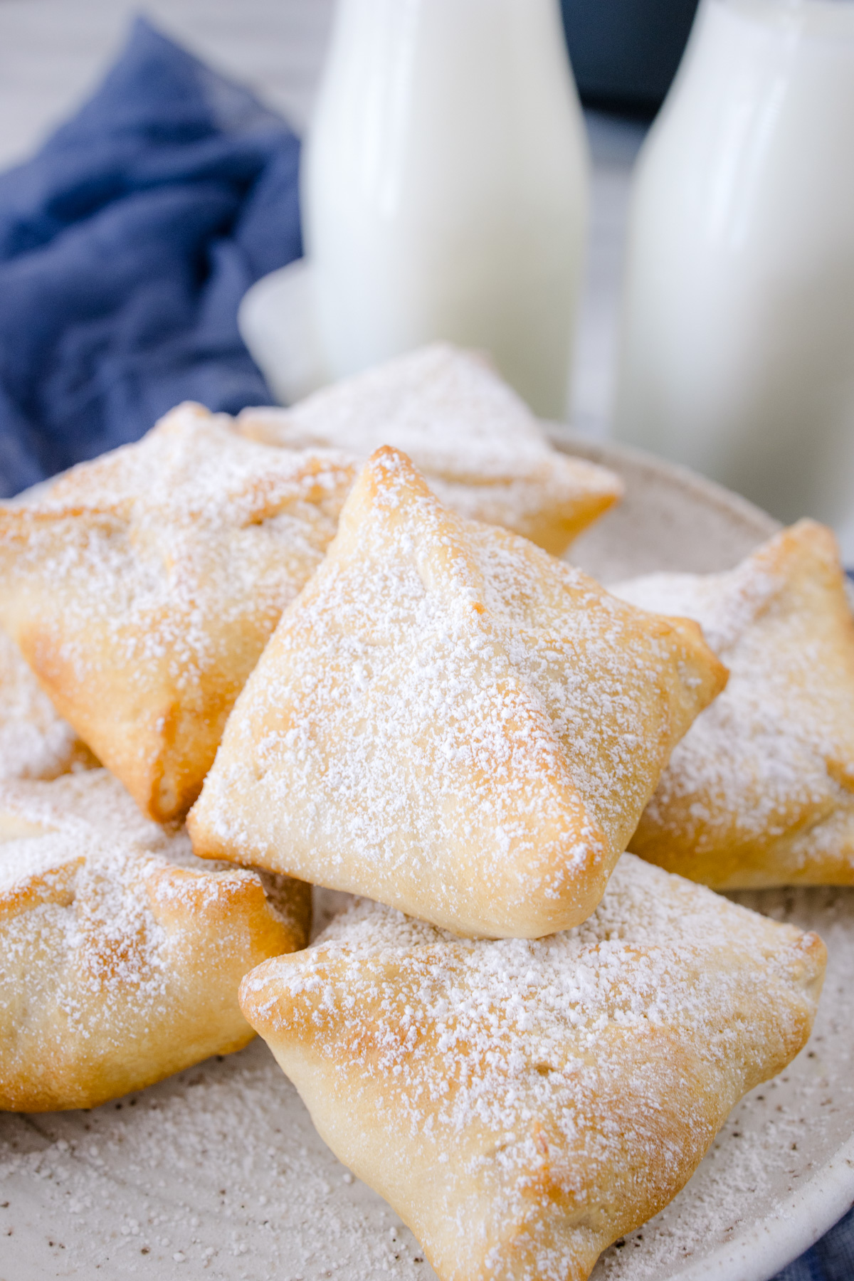 Air Fryer Fried Oreos piled on a plate with powdered sugar dusted on them.