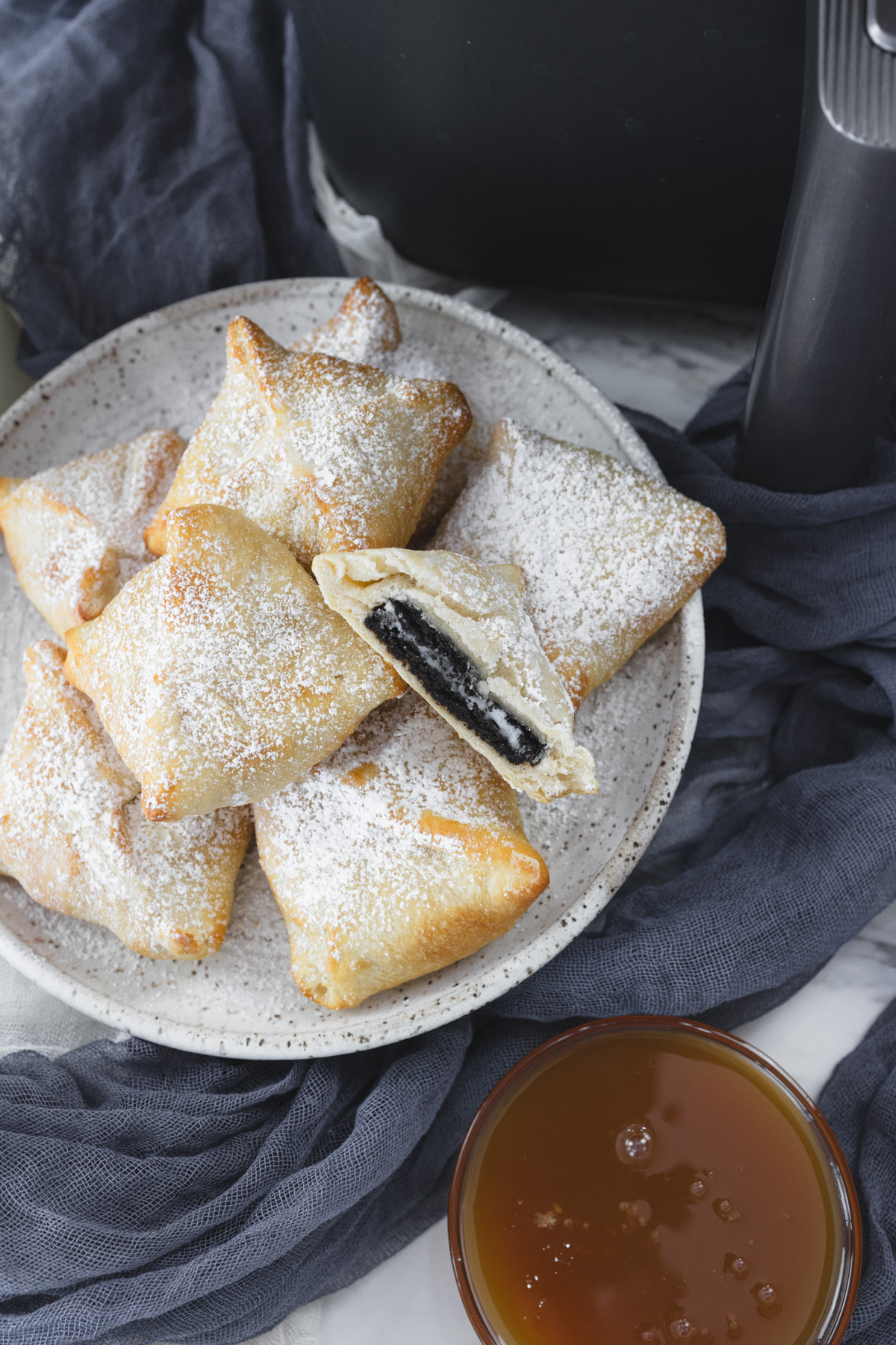 Air Fryer Fried Oreos on a white plate. One is sliced in half, exposing the middle.