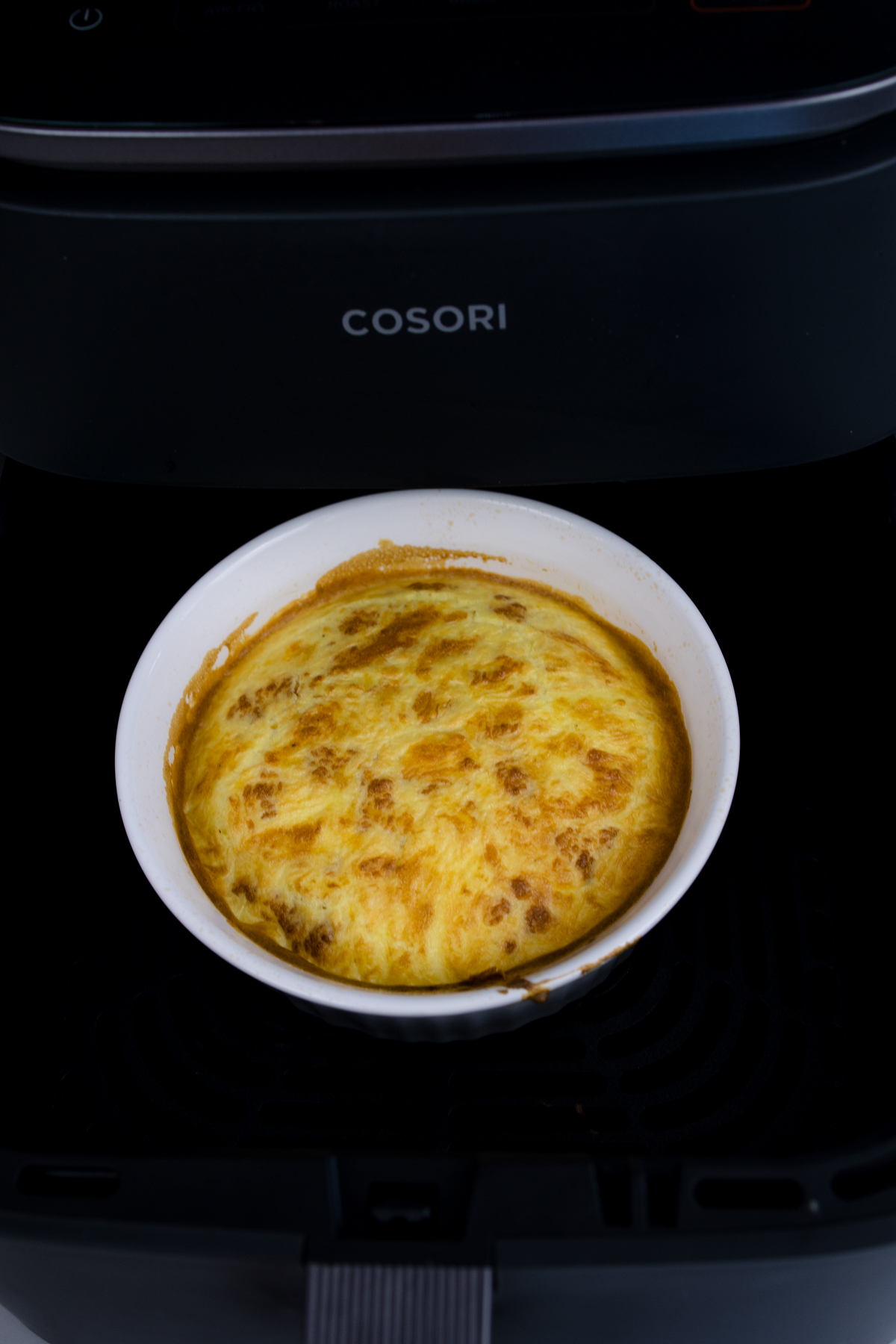 Close up view of cooked scrambled egg mixture in a white bowl in an air fryer.