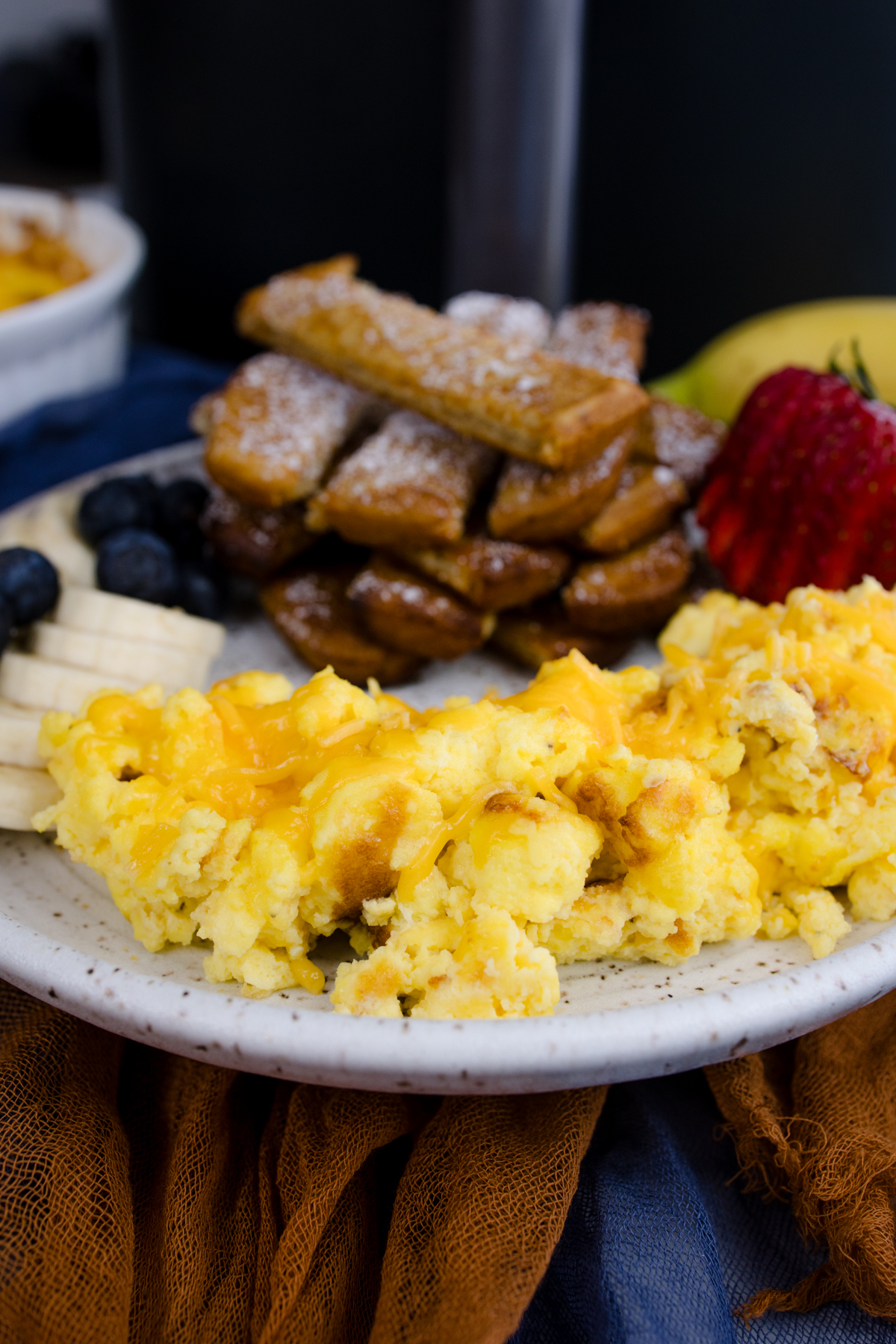 Air Fryer Scrambled Eggs on a white plate with other breakfast items.