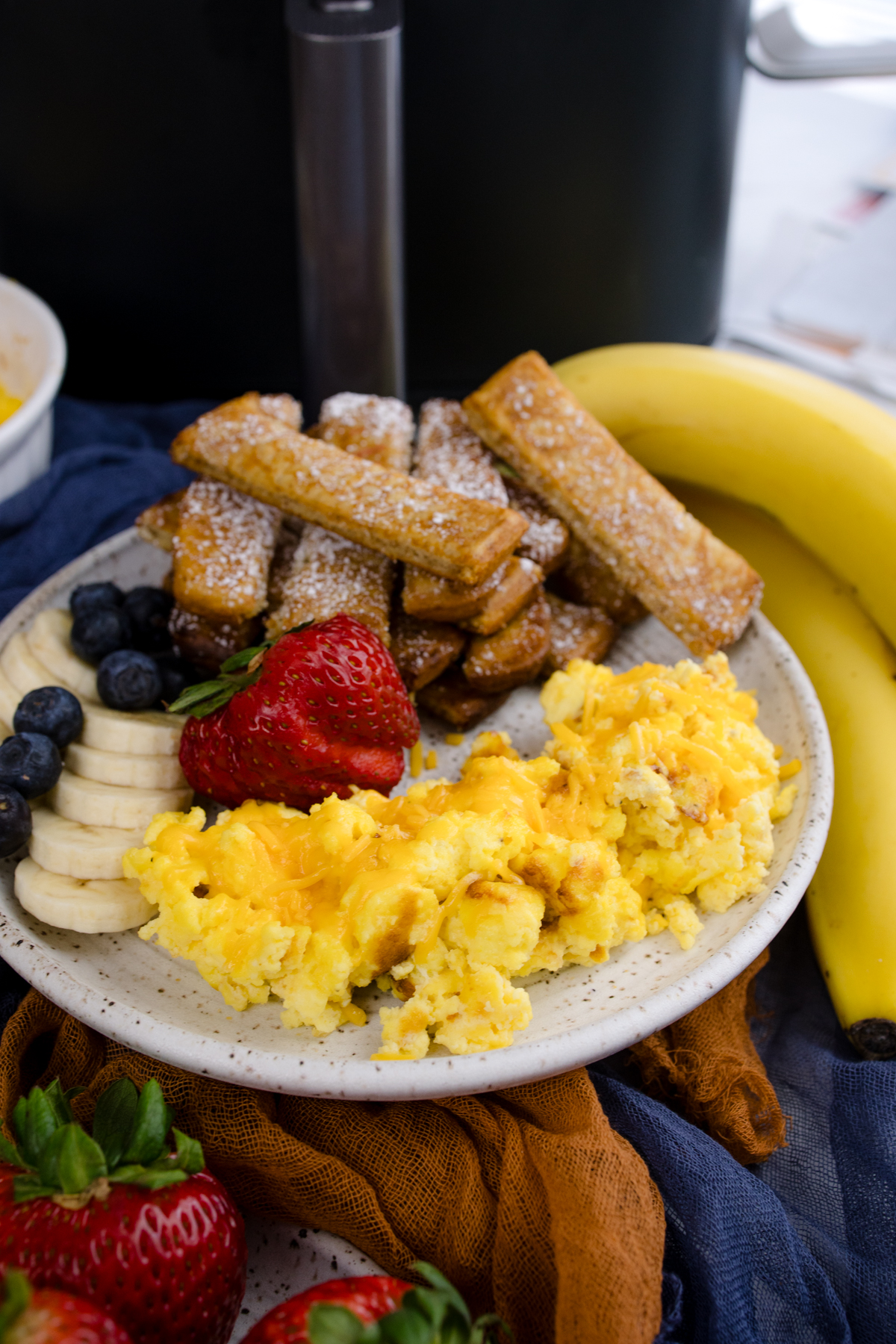 Air Fryer Scrambled Eggs on a white plate with other breakfast items.