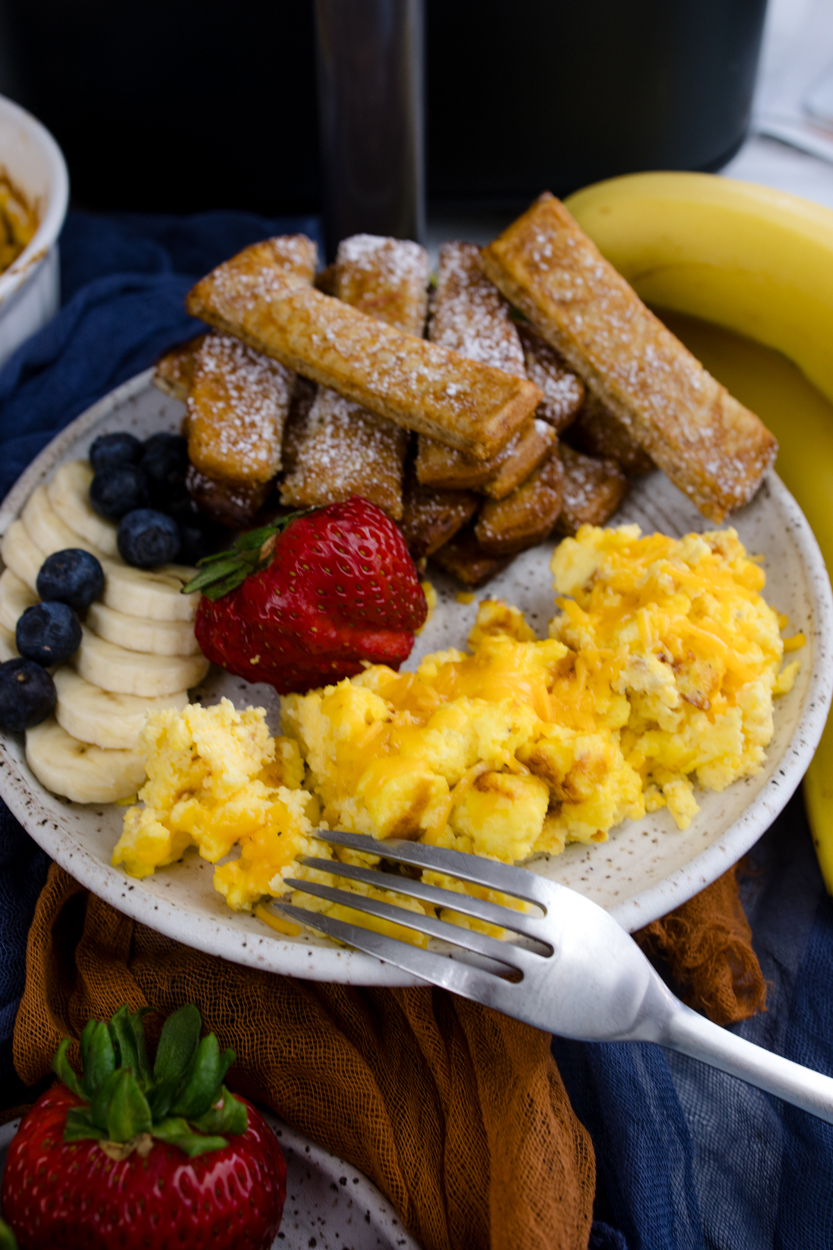 Air Fryer Scrambled Eggs on a white plate with other breakfast items.