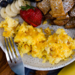 Air Fryer Scrambled Eggs on a white plate with other breakfast items.