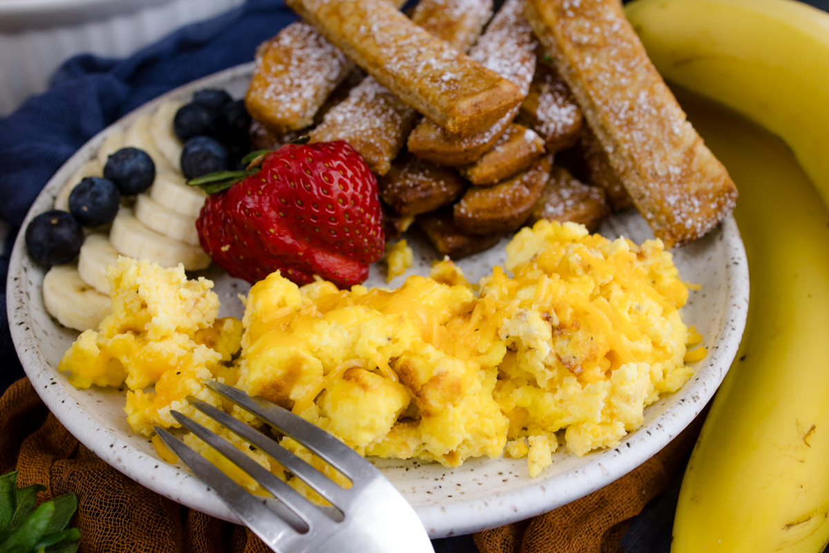 Air Fryer Scrambled Eggs on a white plate with other breakfast items.