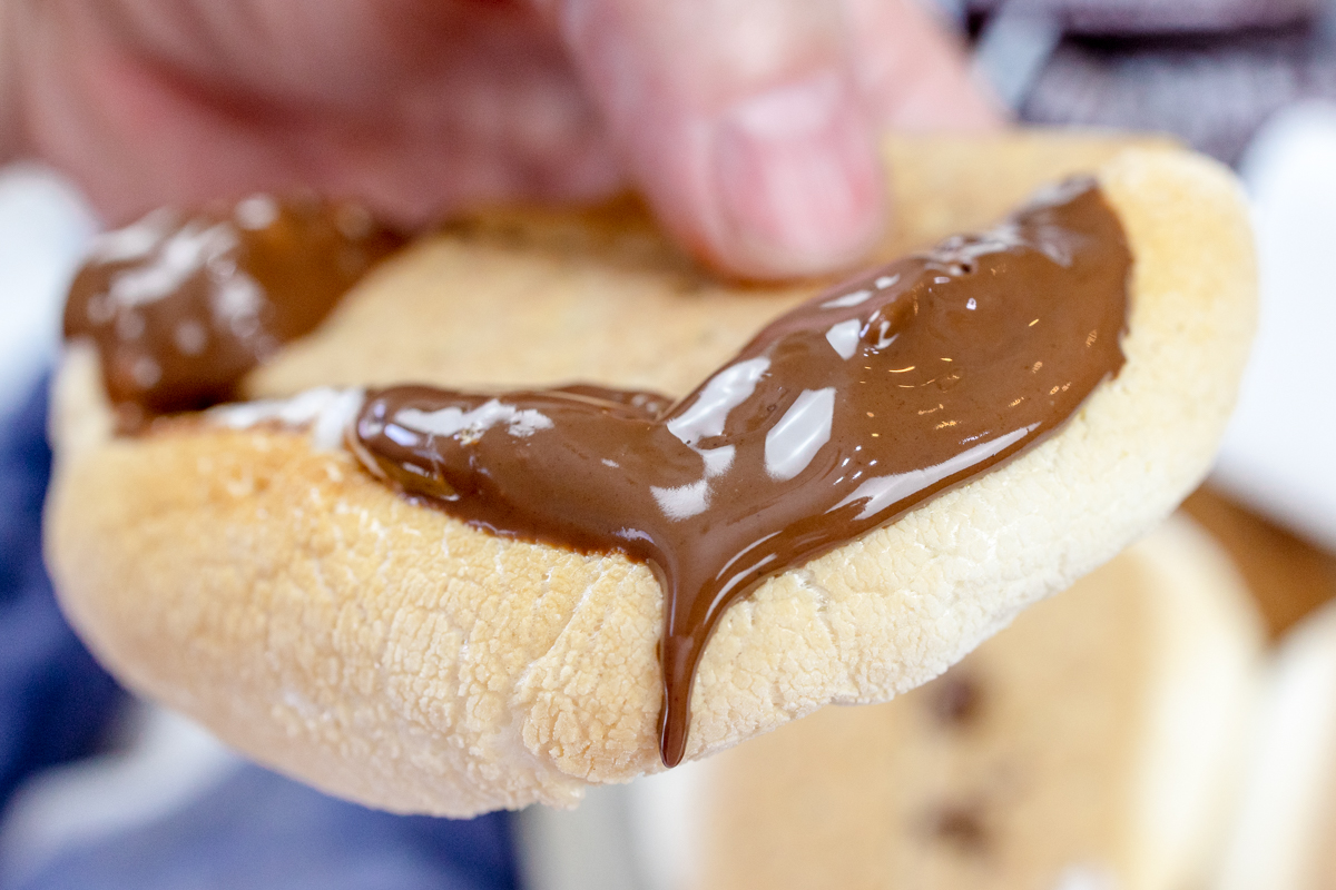 A hand squeezing an Air Fryer Smore so that the melted chocolate and gooey marshmallow spills out of the sides.