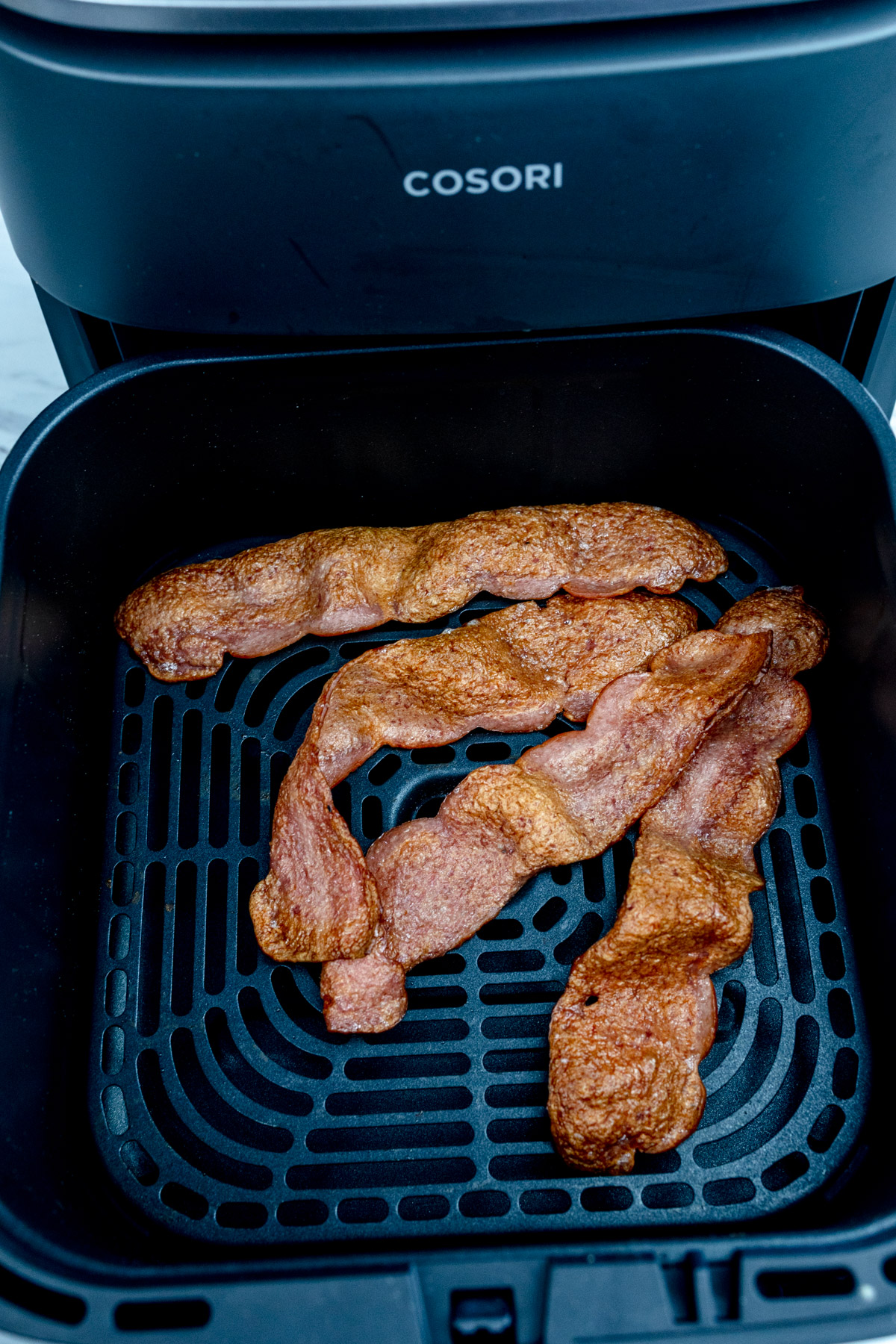 Cooked turkey bacon in an air fryer basket.