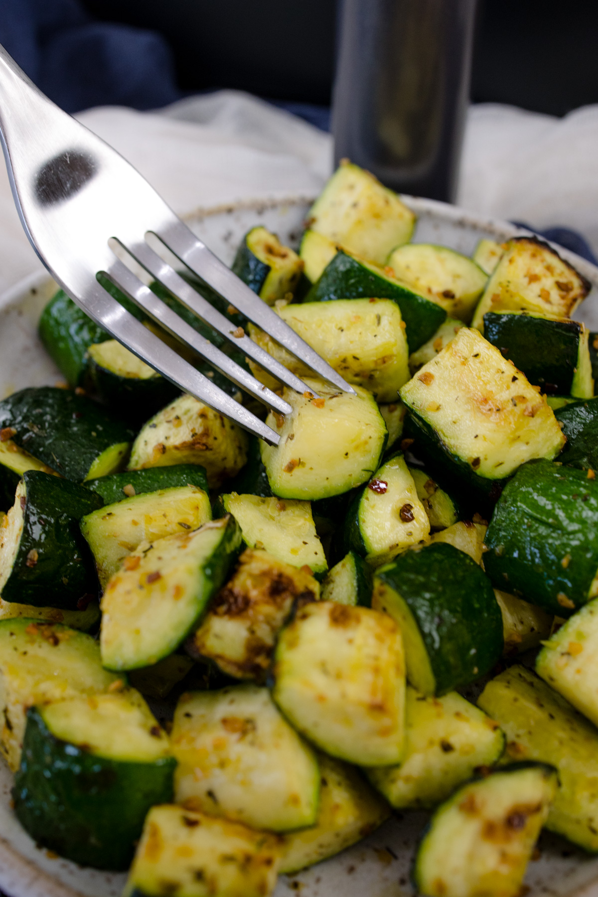 A fork resting on a plate of air fryer zucchini.