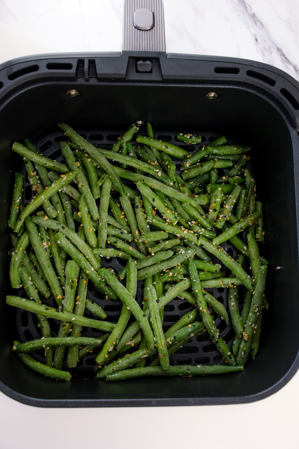 Seasoned green beans in an air fryer.