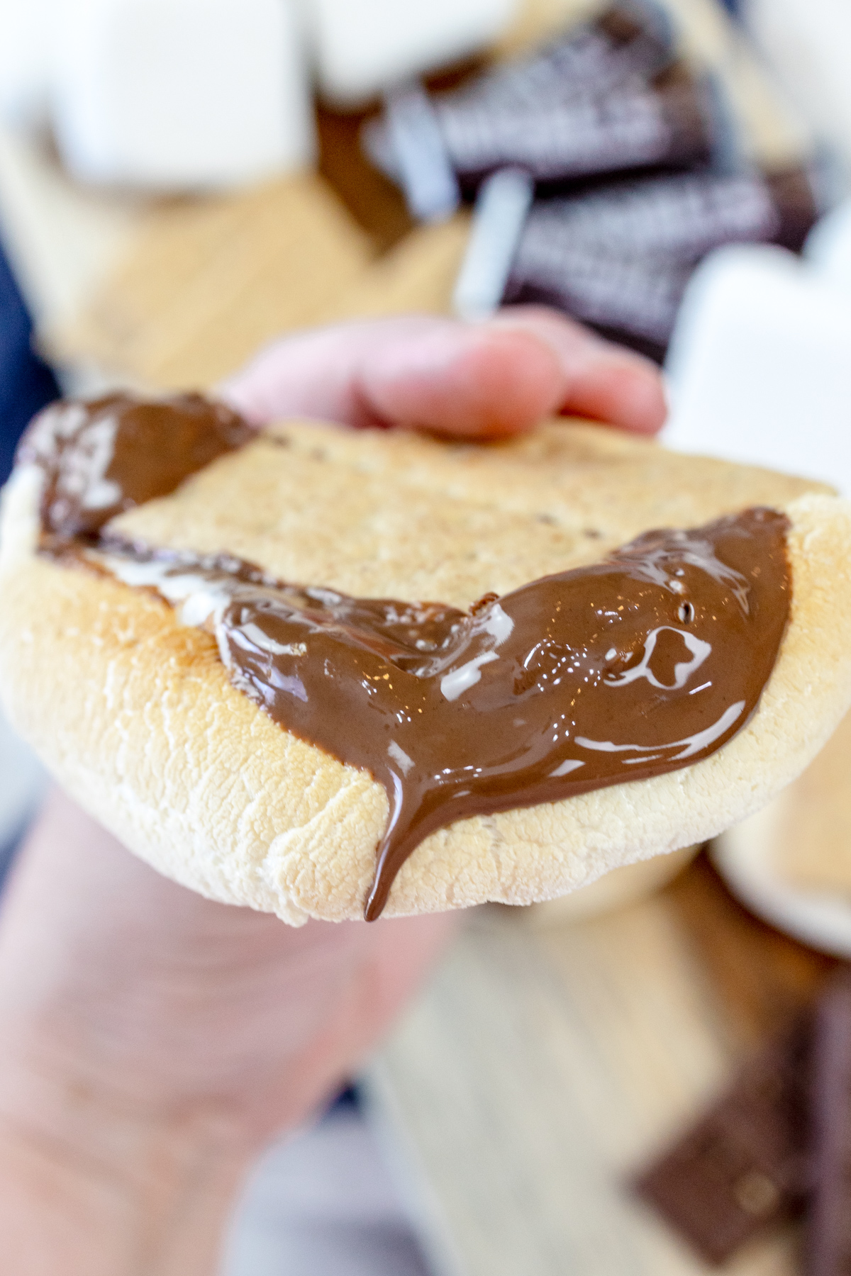 A hand squeezing an Air Fryer Smore so that the melted chocolate and gooey marshmallow spills out of the sides.