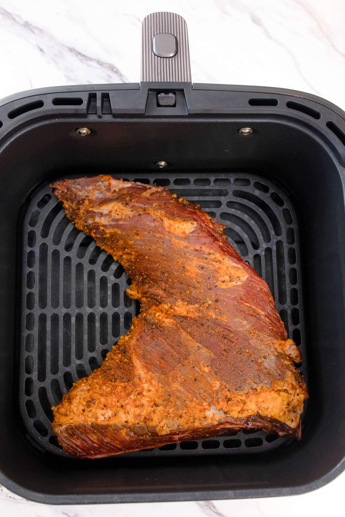 Seasoned Tri Tip Roast in an air fryer basket.