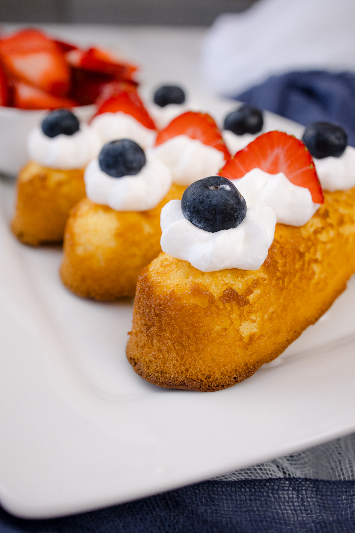 Air Fryer Twinkies topped with whipped cream and berries, on a white serving plate.