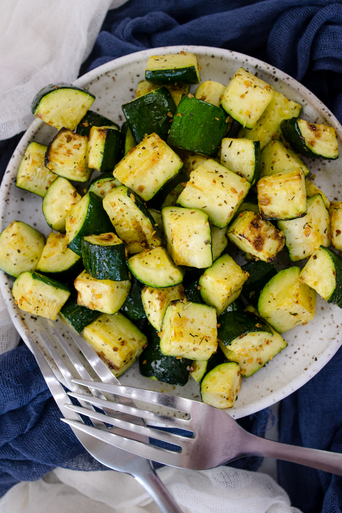 Air Fryer Zucchini on a white plate with a silver fork in the foreground.