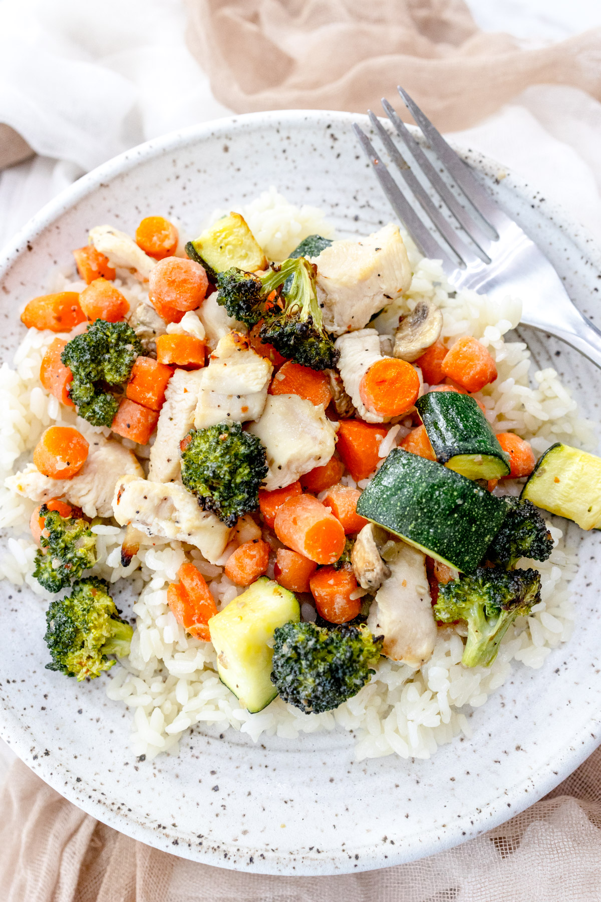 Air Fryer Chicken and Vegetables on a white plate with a silver fork on it.