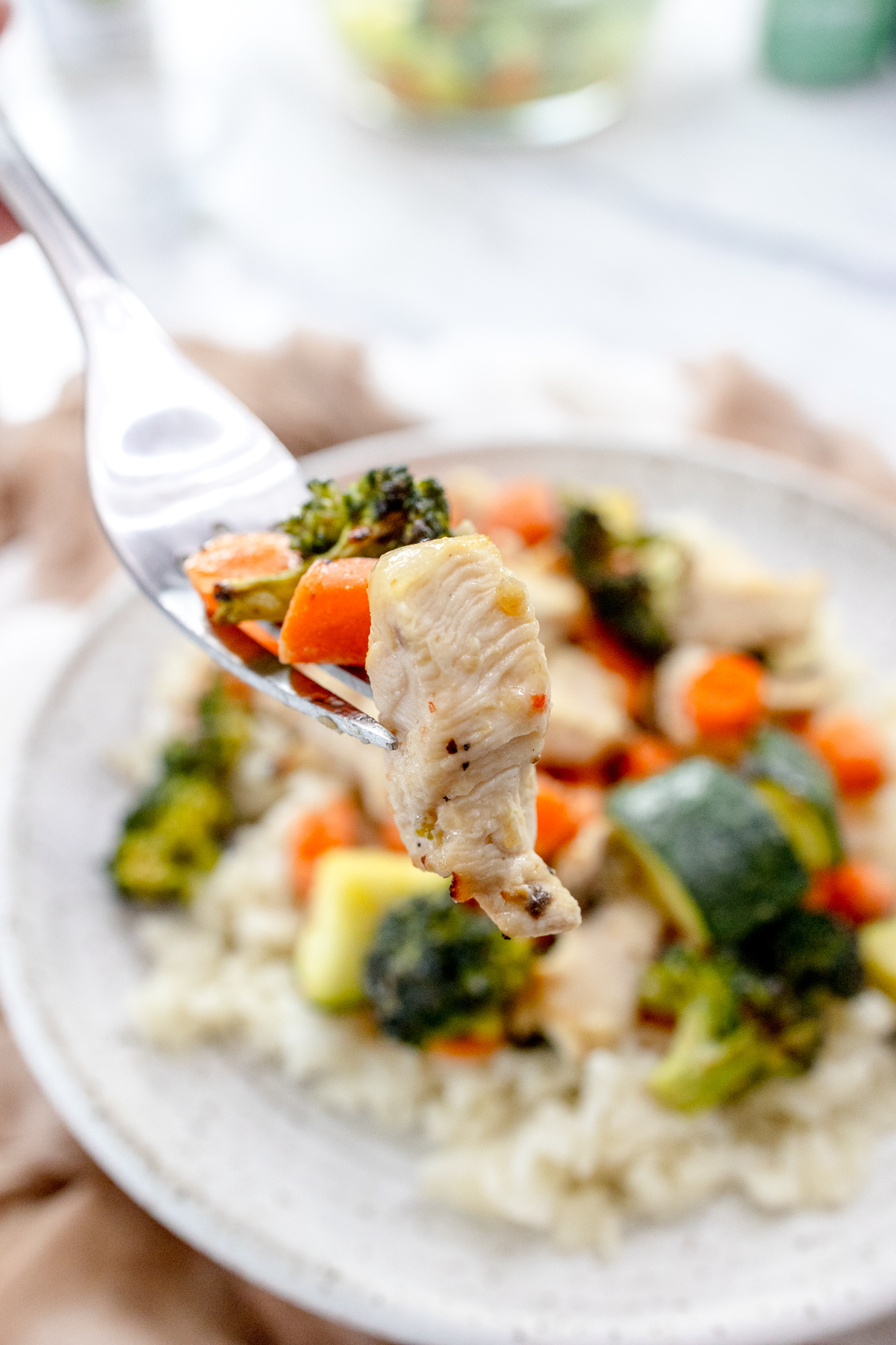 Air Fryer Chicken and Vegetables on a white plate with a silver fork scooping a forkful up.